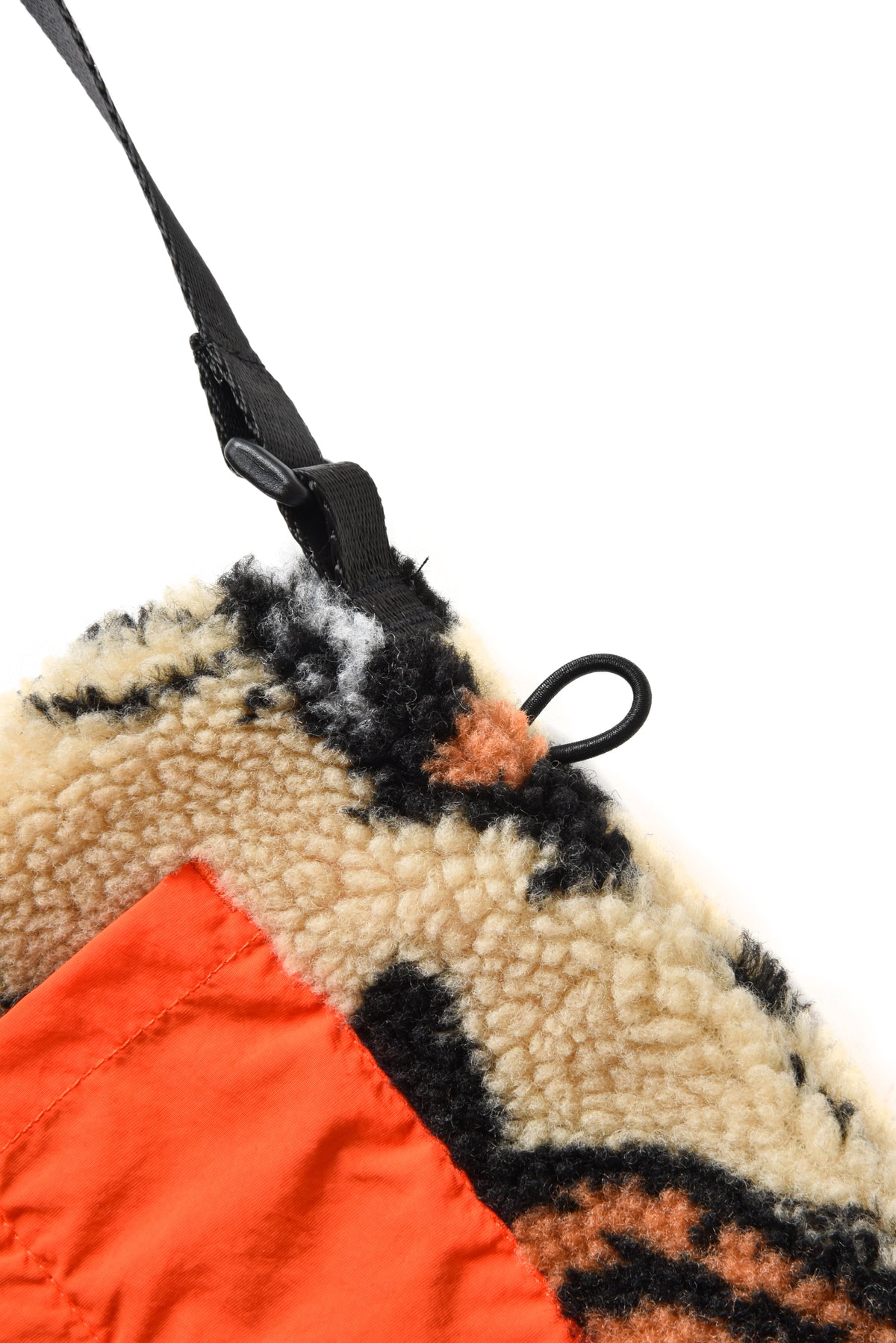 Close-up of a textured fabric with orange corner and black strap on a white background