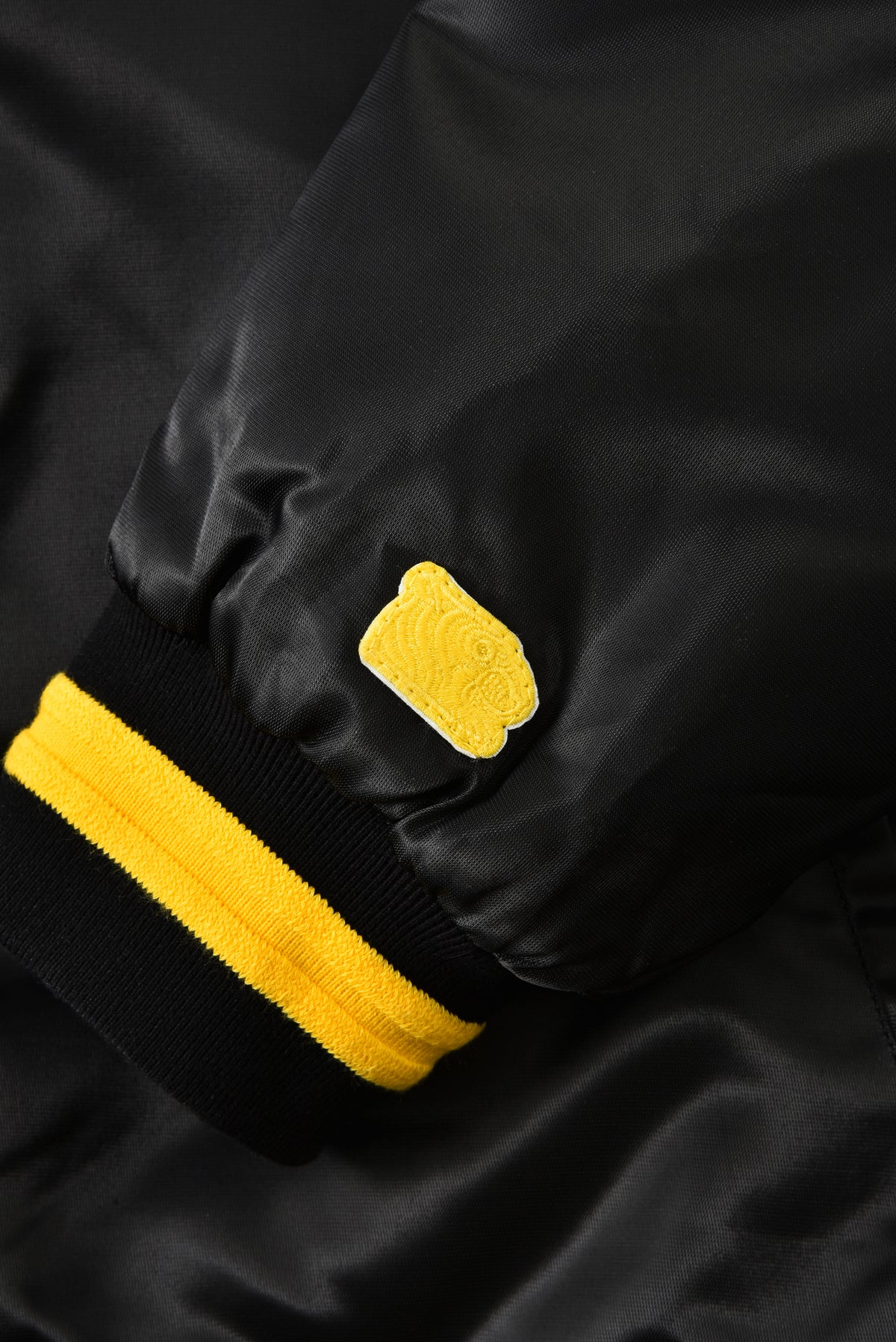 Black jacket with yellow accents and yellow soulgoods tiger head on a dark background