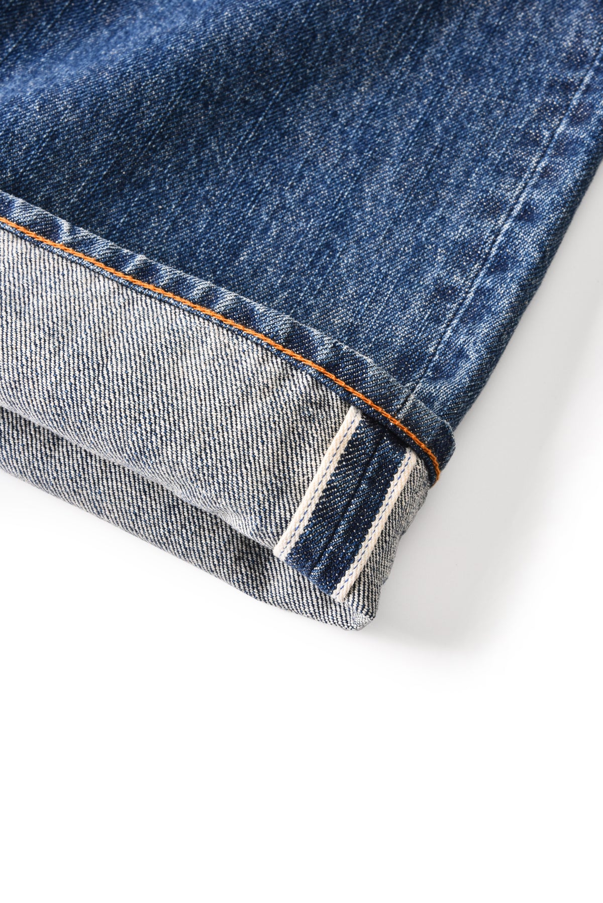 Close-up of a folded blue denim jeans edge on a white background