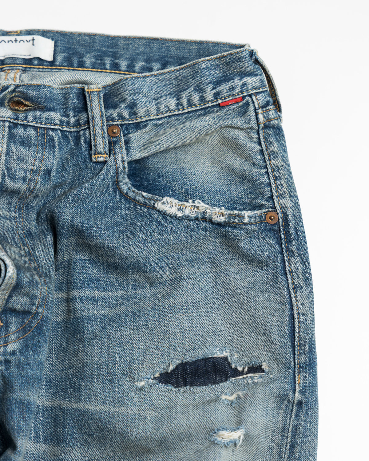 Close-up of a pair of blue jeans with a brand label on a white background