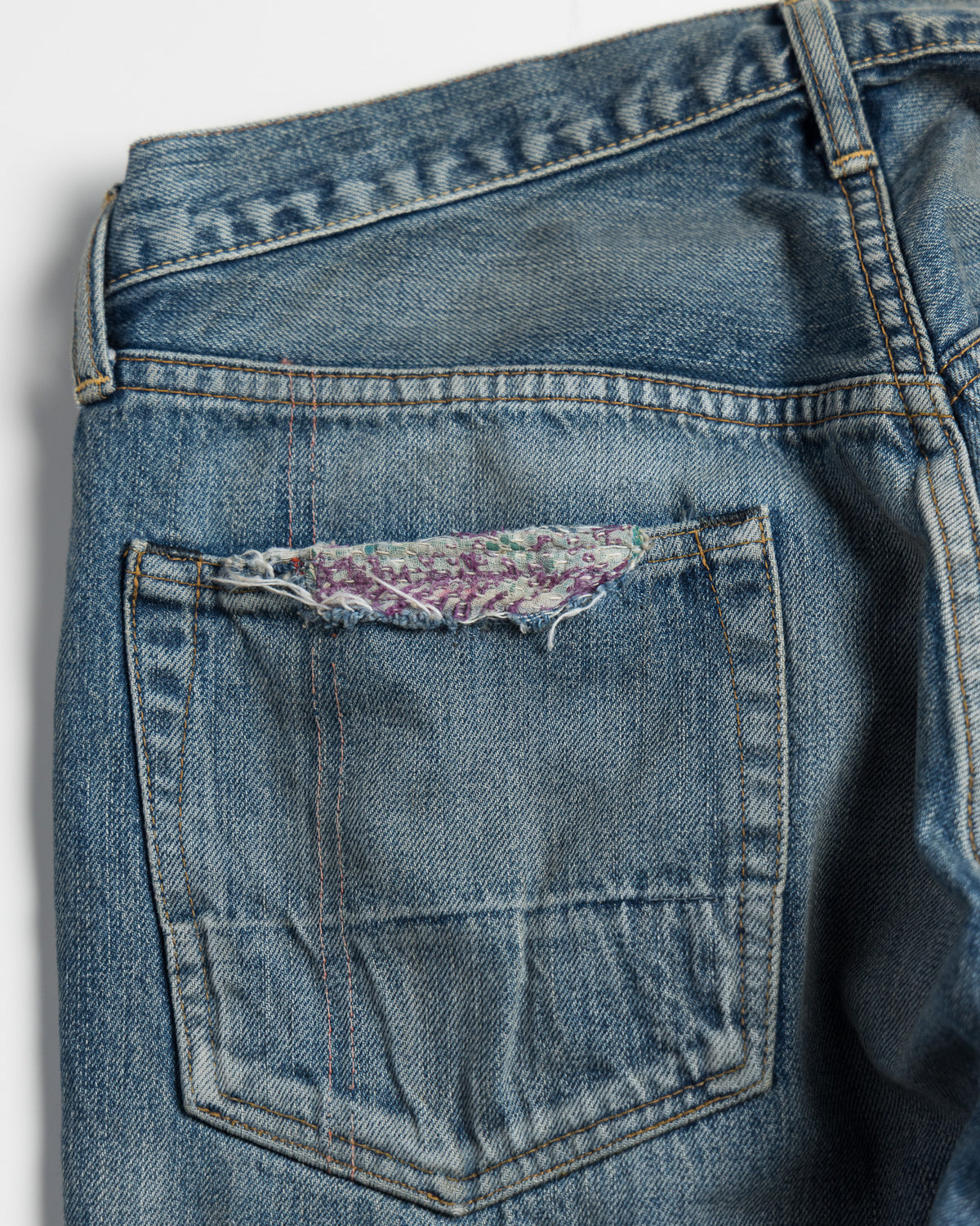 Close-up of a blue denim pocket with floral lining on a gray background