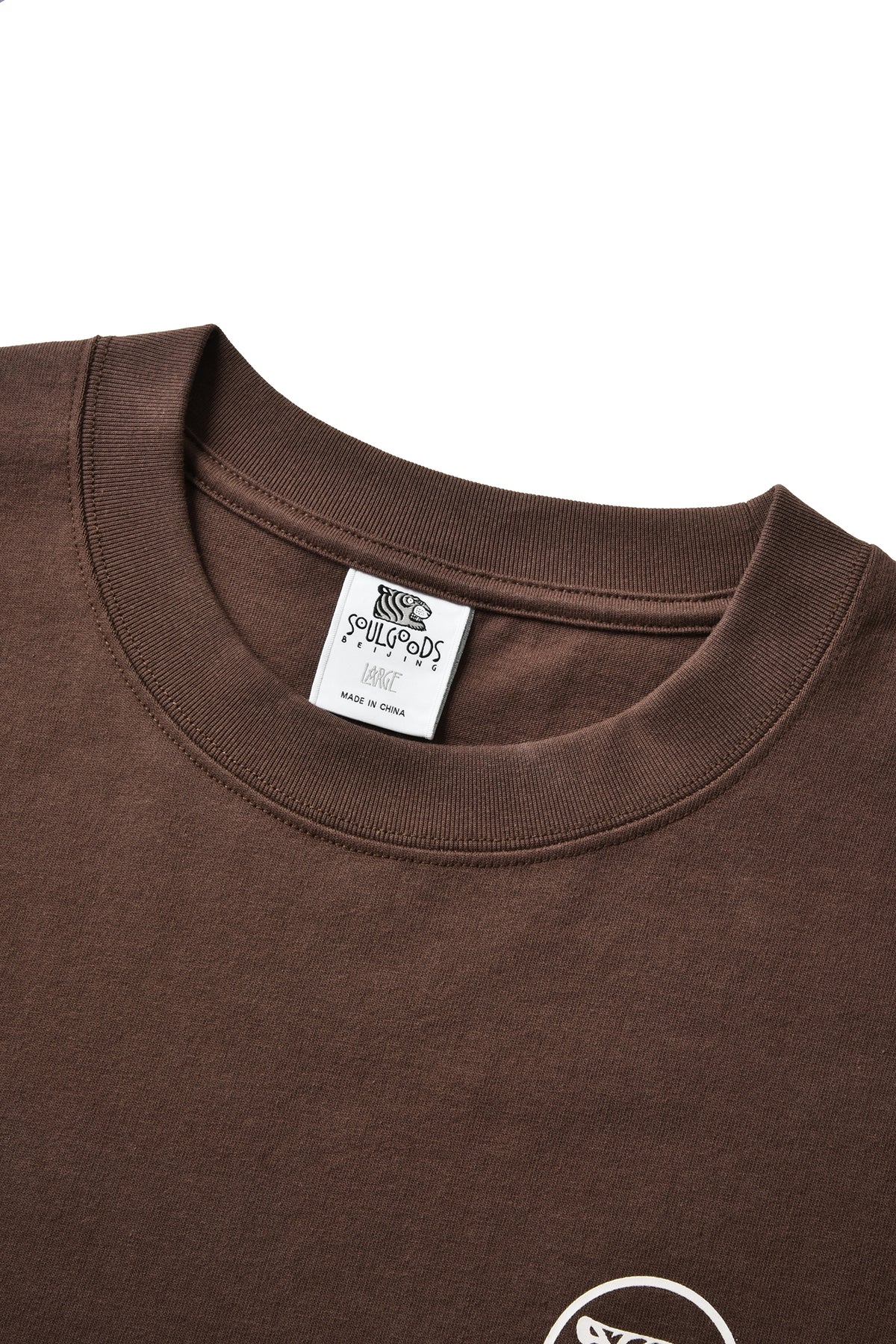 Close-up of a brown crewneck t-shirt showing the inner neck label read 'SOULGOODS' and 'Large'