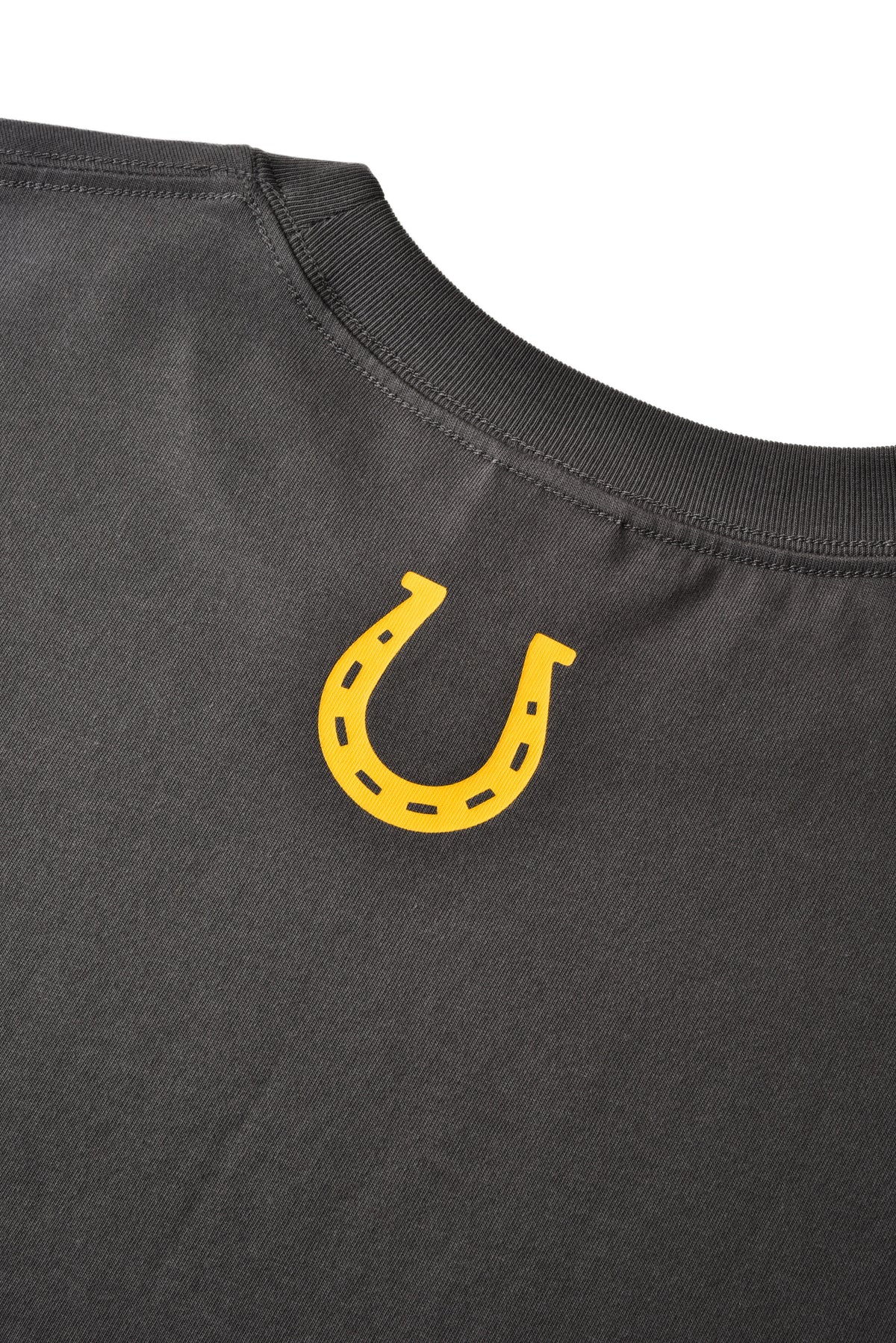 Close-up of a black shirt with a yellow horseshoe emblem on a white background
