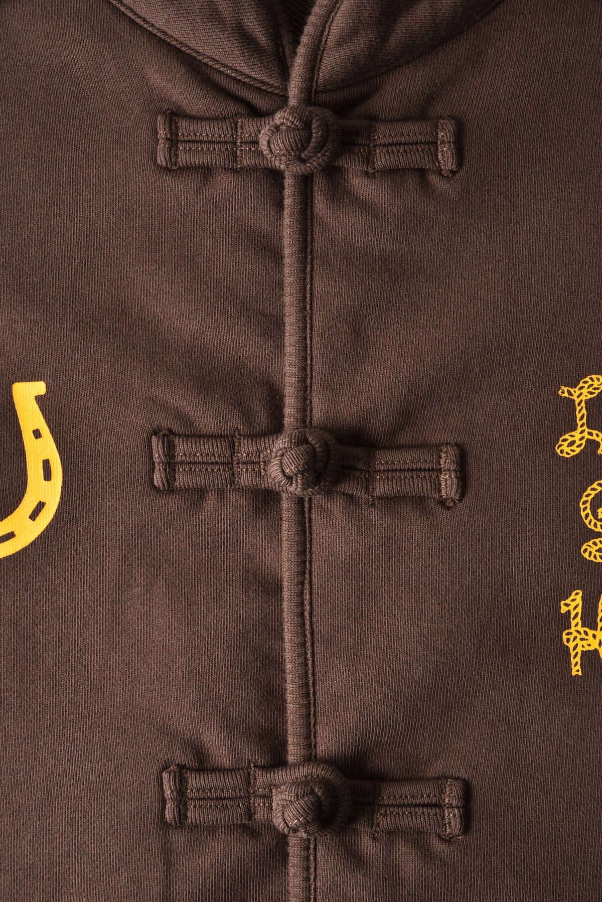 Close-up of a brown jacket with yellow horseshoe designs on a matching background