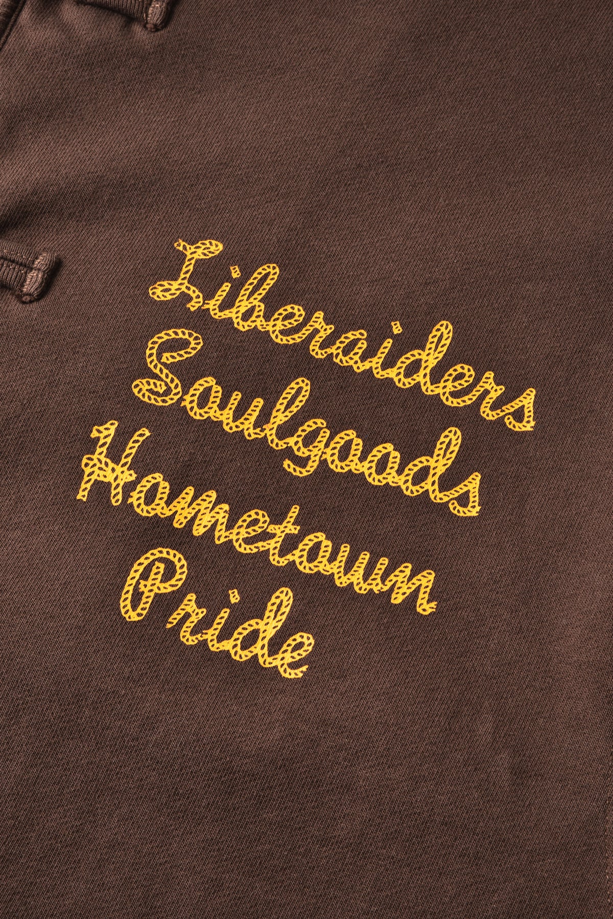 Brown jacket with yellow embroidered text "Liberaiders SOULGOODS Hometown Pride" on a bown background