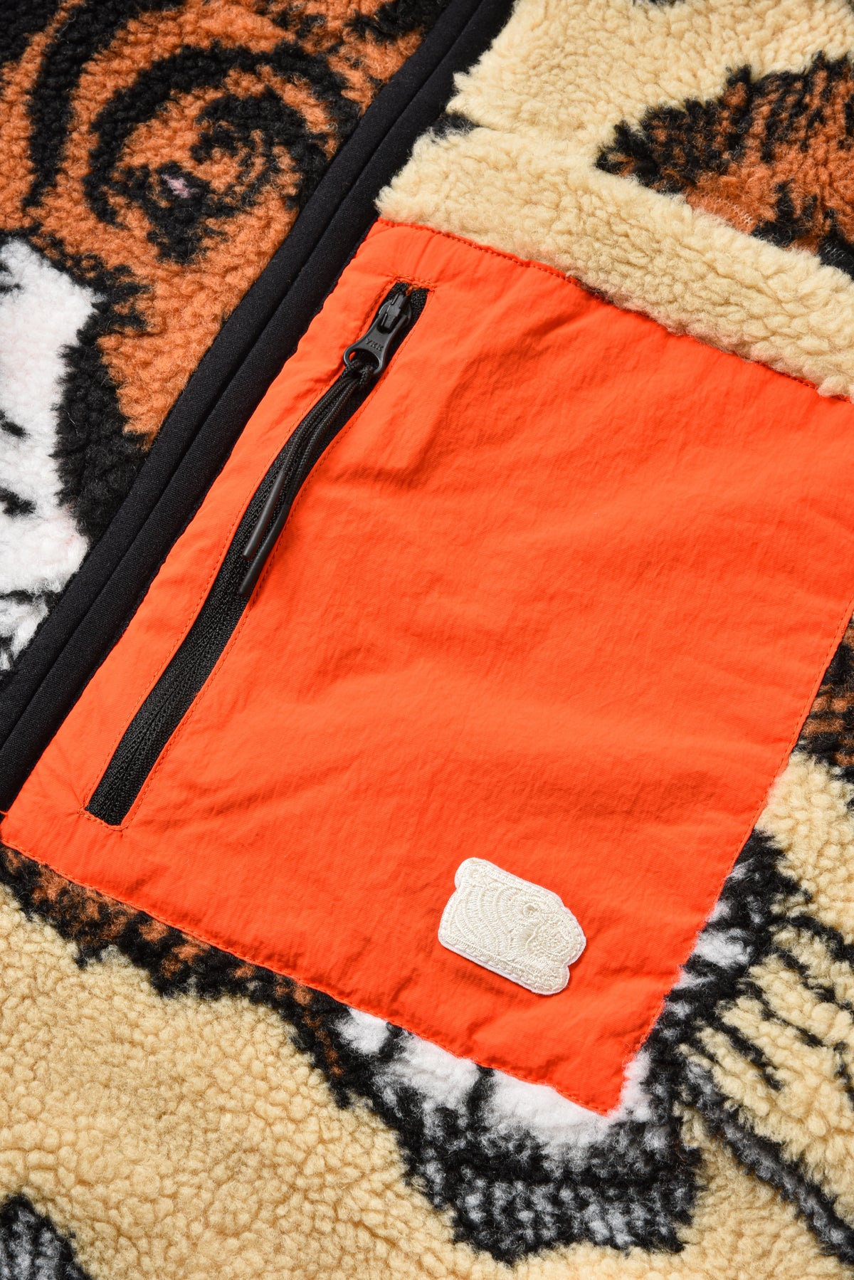 Close-up of an orange jacket with a black zipper on a patterned background