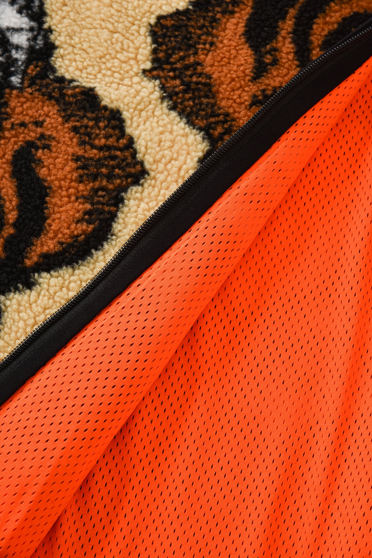 Close-up of a tiger patterned fabric with a zipper and orange mesh material.