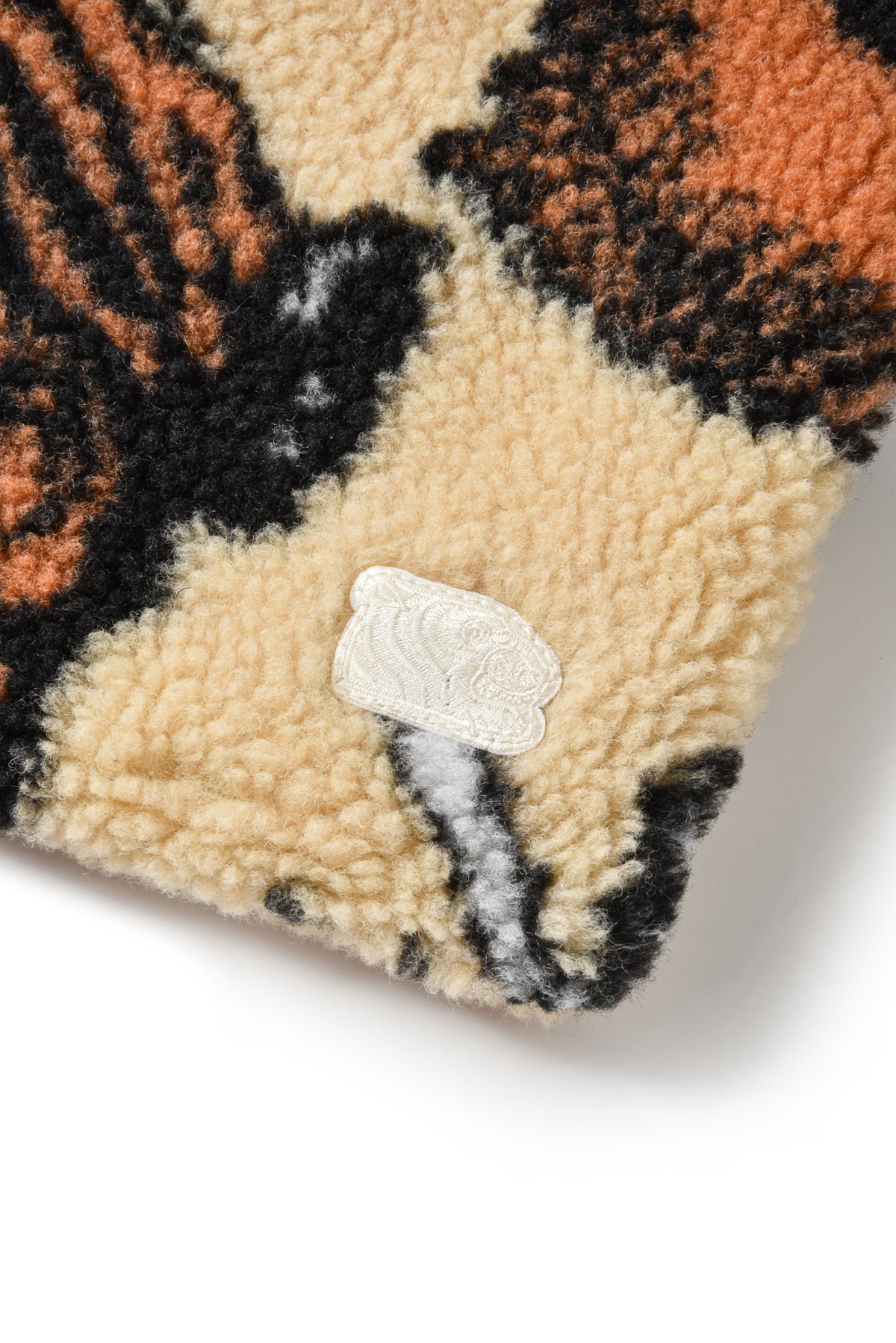 Close-up of a textured fabric with a pattern and a brand logo on a white background