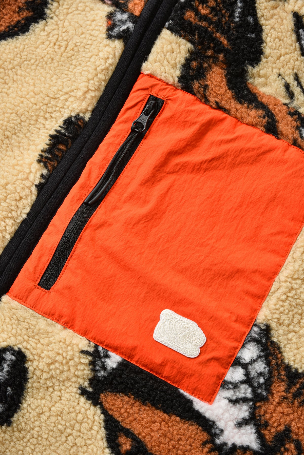 Orange bag with a black zipper on a textured surface
