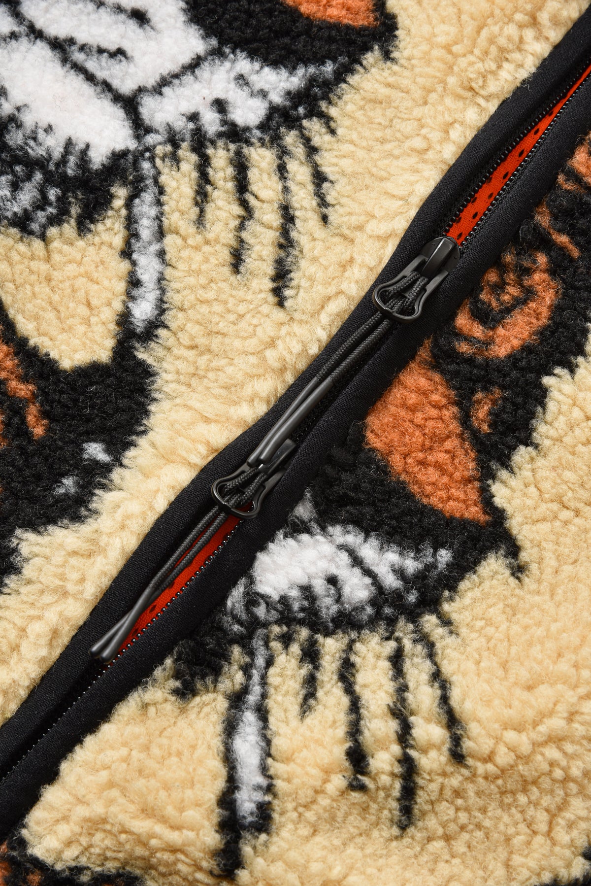 Close-up of a textured fabric with a zipper, featuring abstract patterns in black, white, and orange.