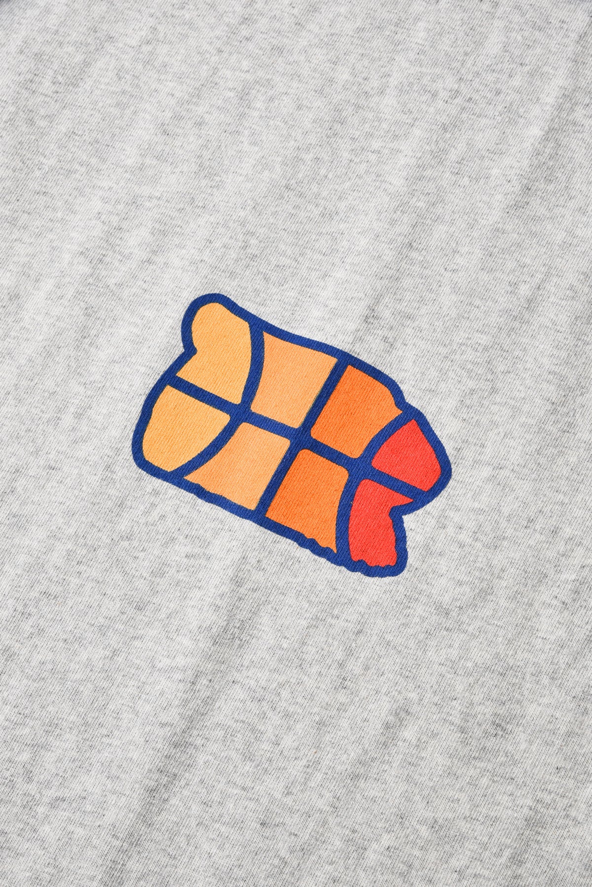A close-up of a heather gray fabric surface featuring a stylized graphic of a croissant in orange, red, and yellow with a dark blue outline.