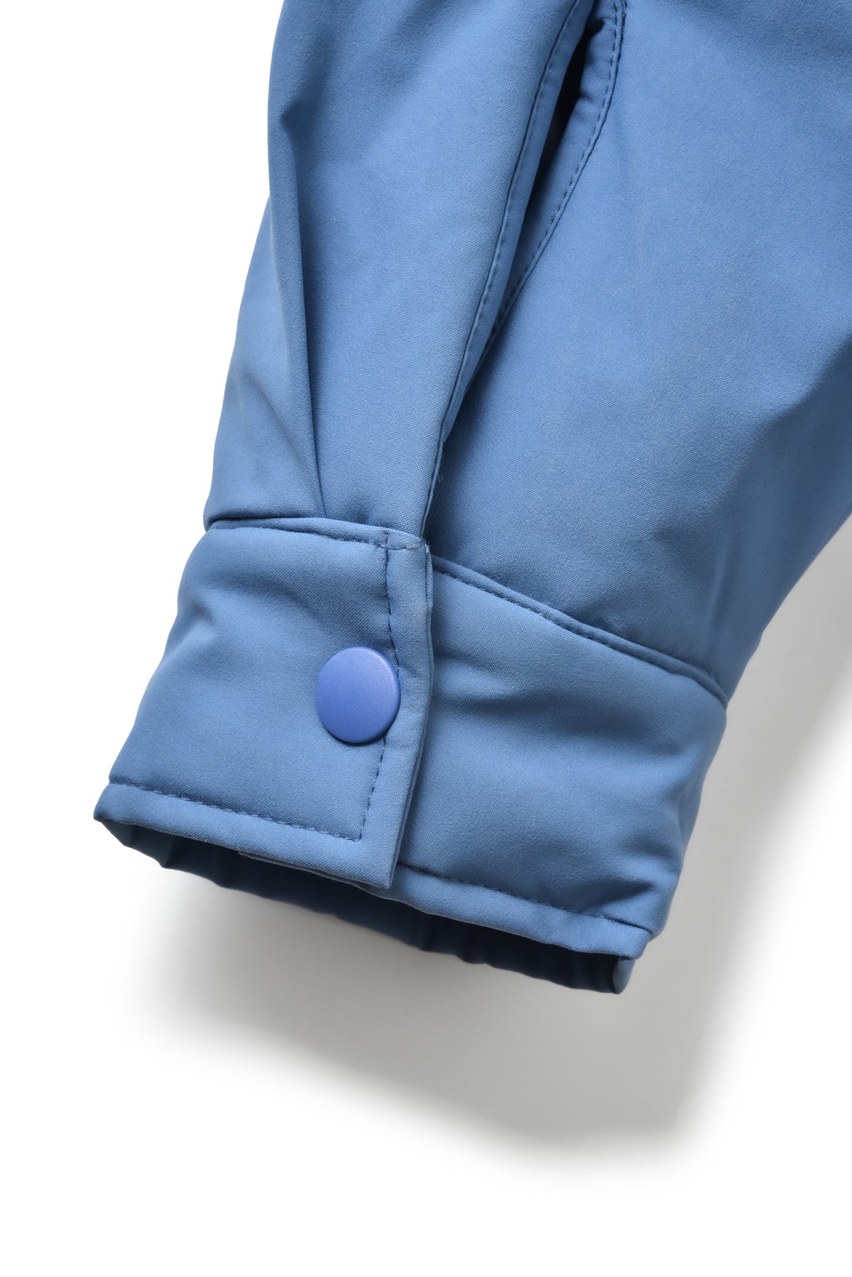 Close-up of a blue jacket with a button on a light gray background