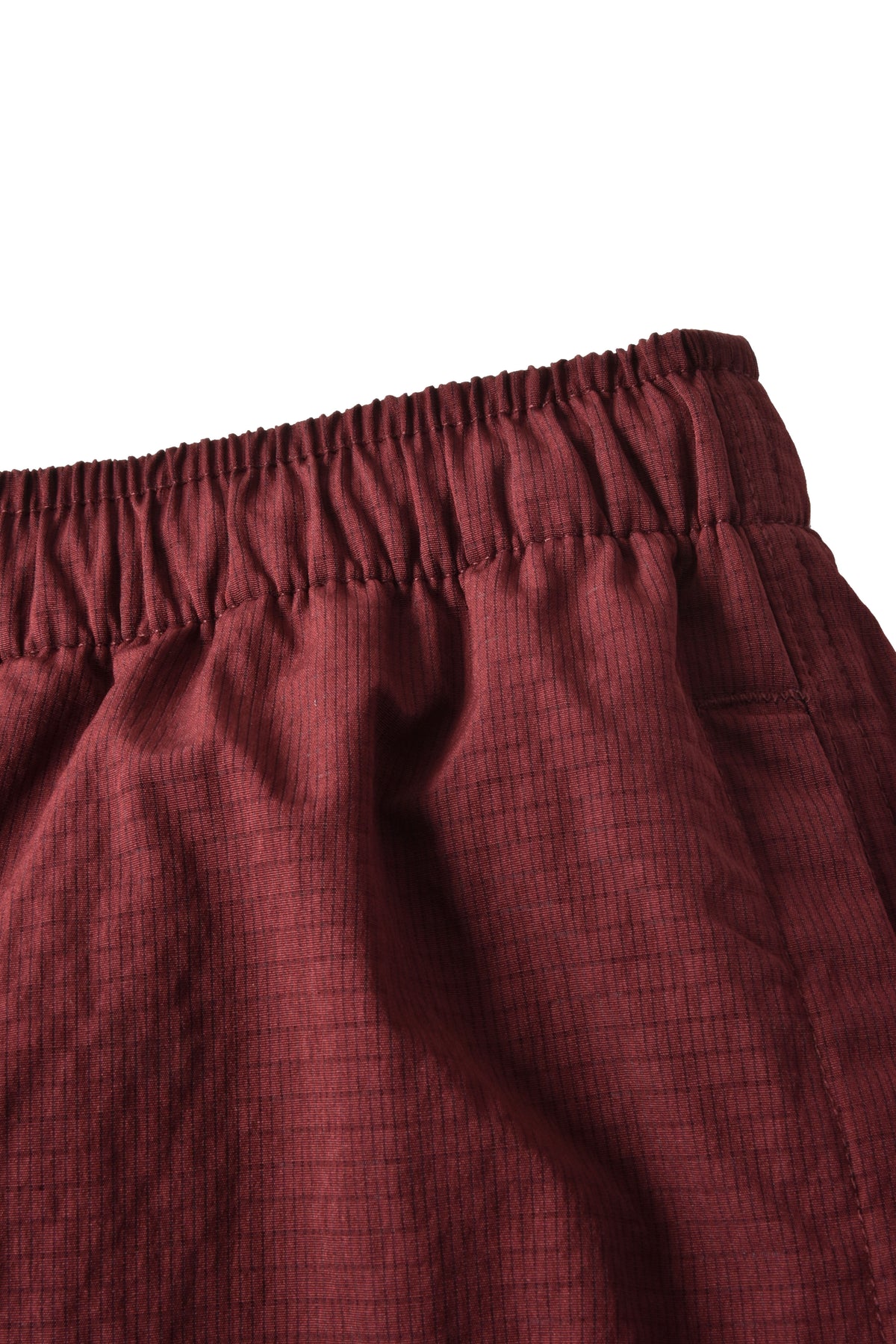 Close-up of a burgundy elastic waistband with a subtle grid texture on a white background.