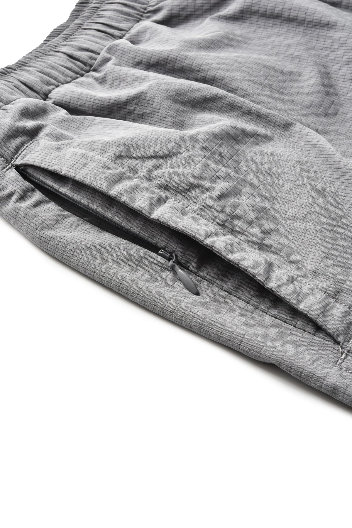 Close-up of gray textured fabric with an elastic waistband and a zippered pocket on a white background.