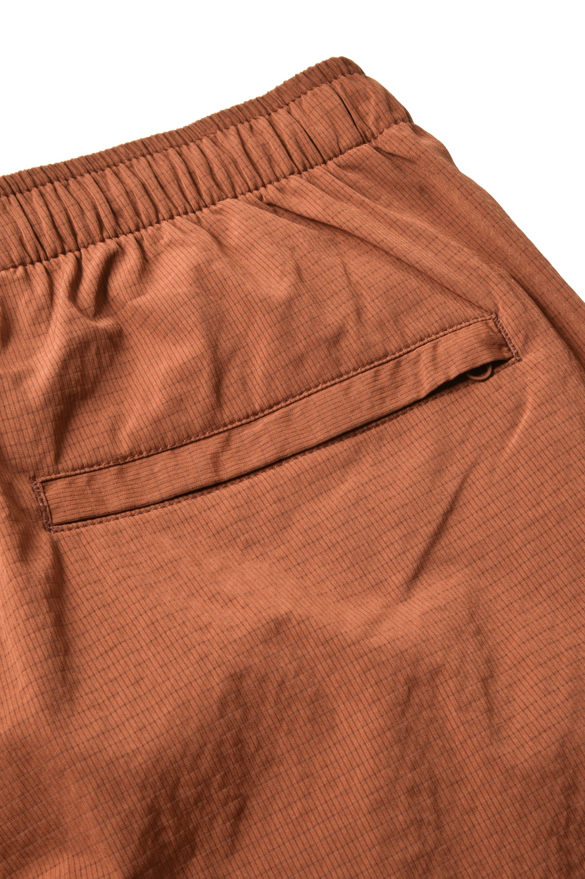 Close-up of a pair of textured brown shorts showing the elastic waistband and a side pocket, set against a plain white background.