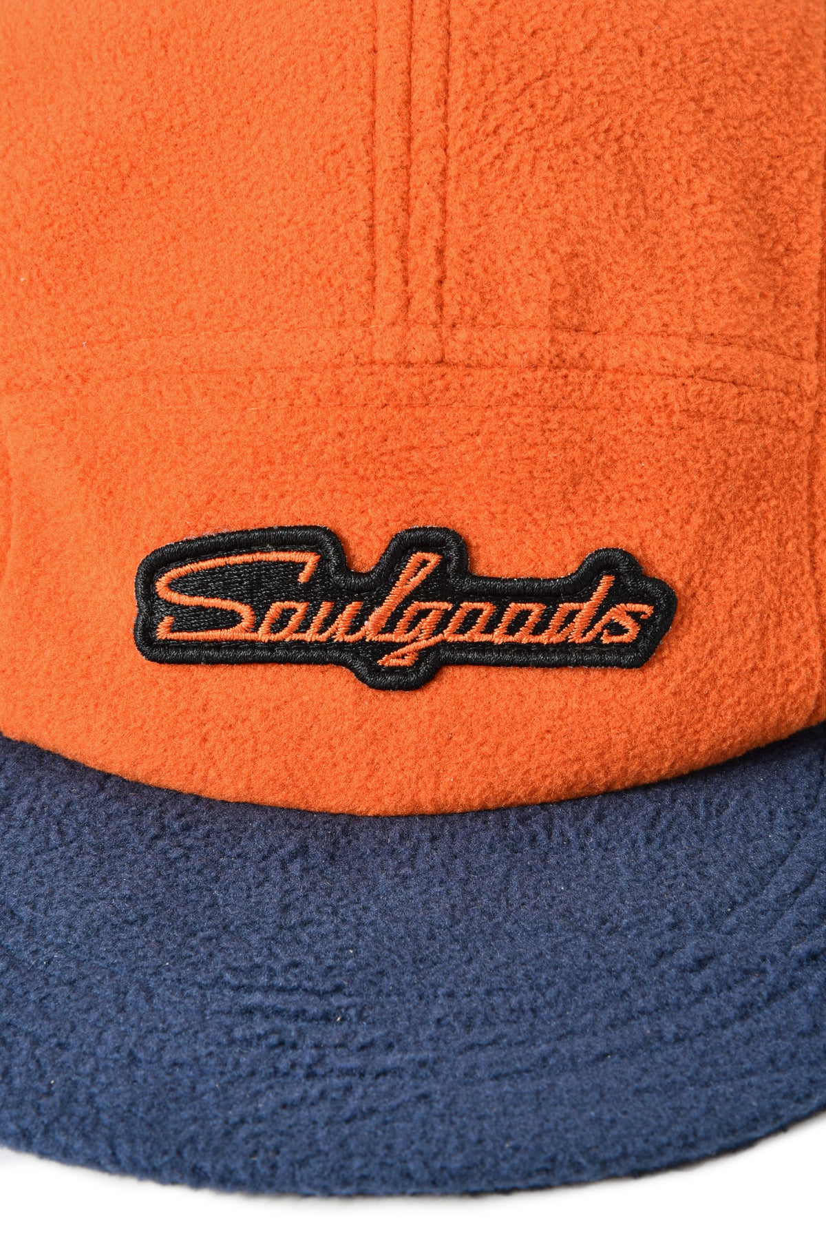 Close-up of an orange and blue fleece jacket with 'Soulgoods' logo.