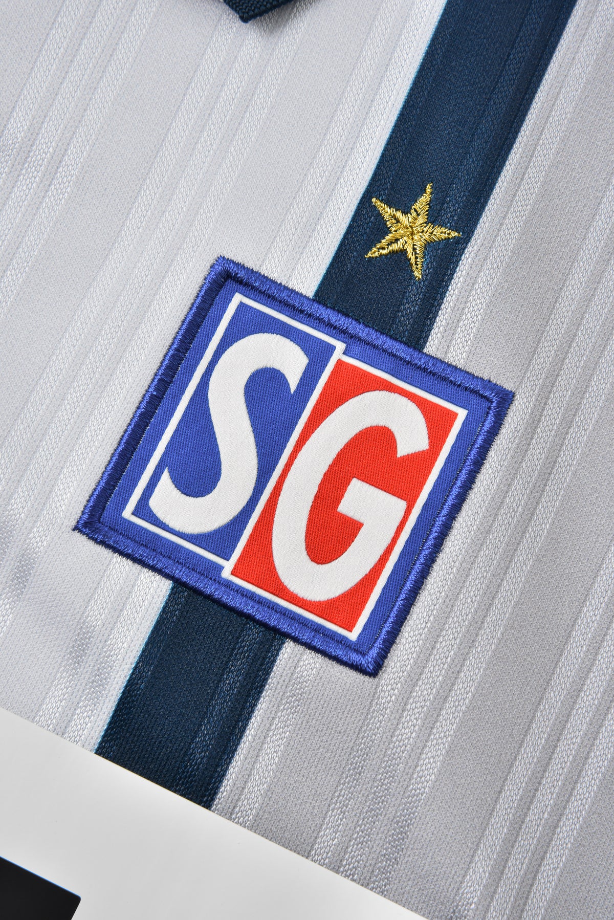 SG logo patch on a sports jersey with a star detail