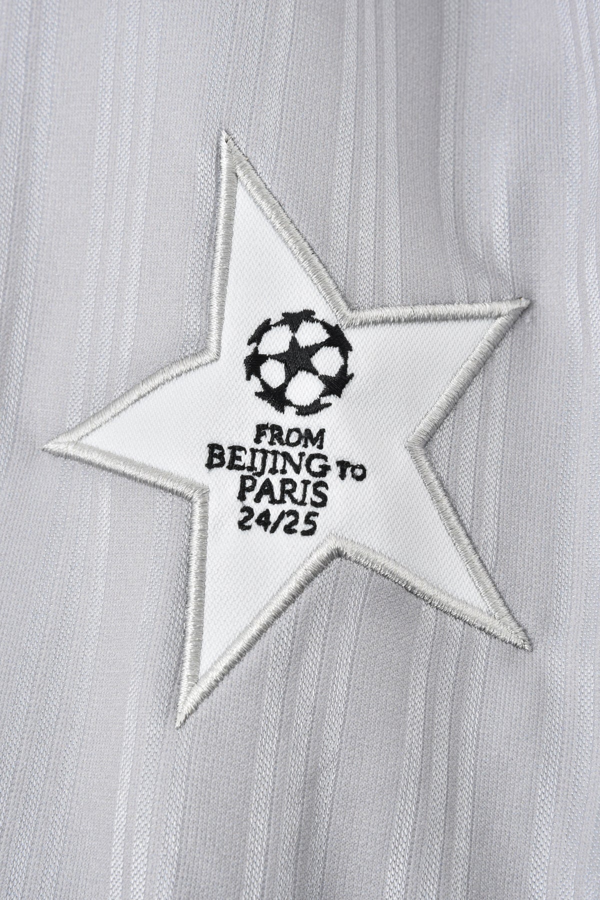 Star-shaped patch with text"from beijing to paris" and logo on a textured gray background