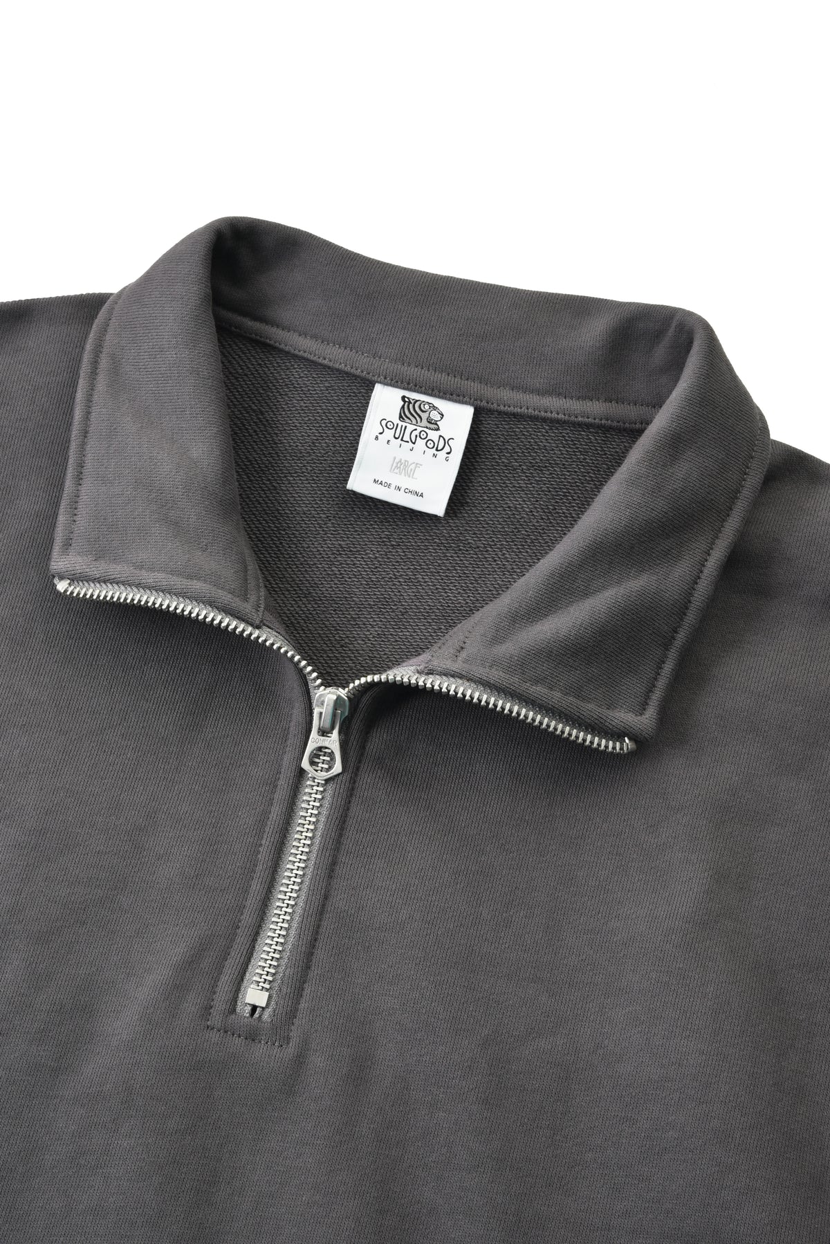 Close-up of a gray fleece pullover with a zipper and collar detail on a white background.