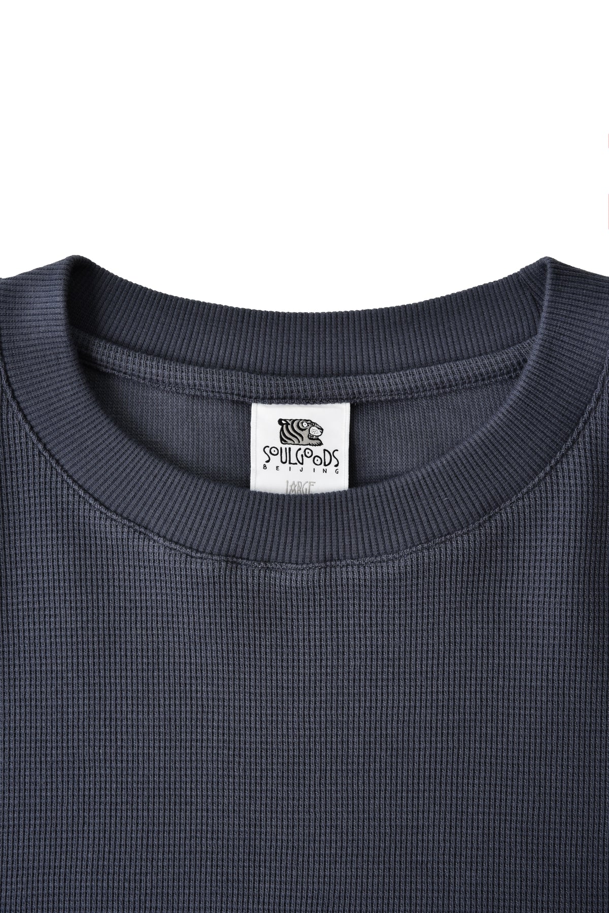 Close-up of a dark gray shirt with a brand label on a white background