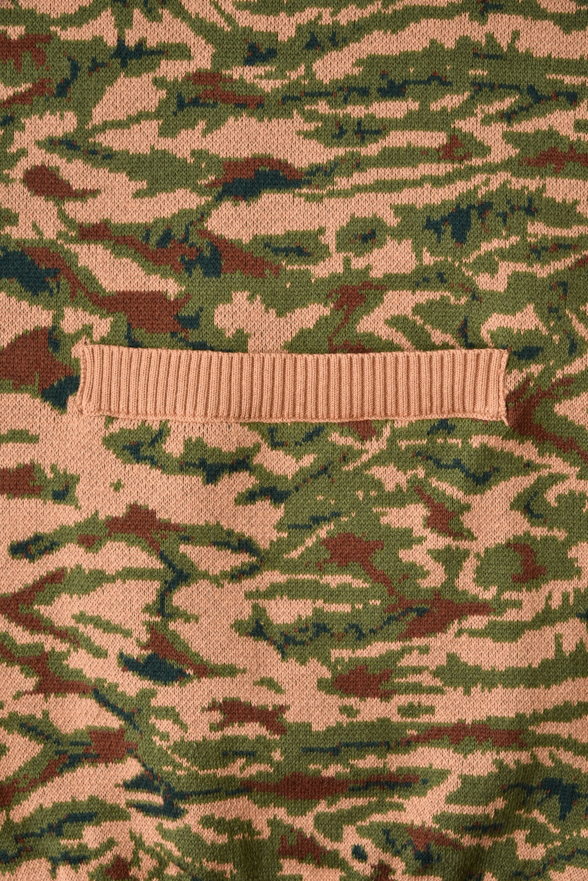Camouflage-patterned fabric with a rectangular beige object on top.