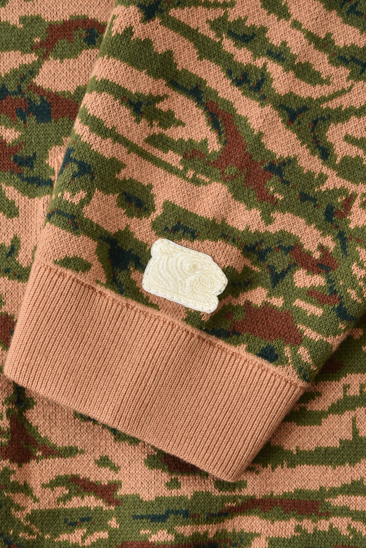 Camouflage-patterned fabric with a soulgoods tiger head logo on a close-up view