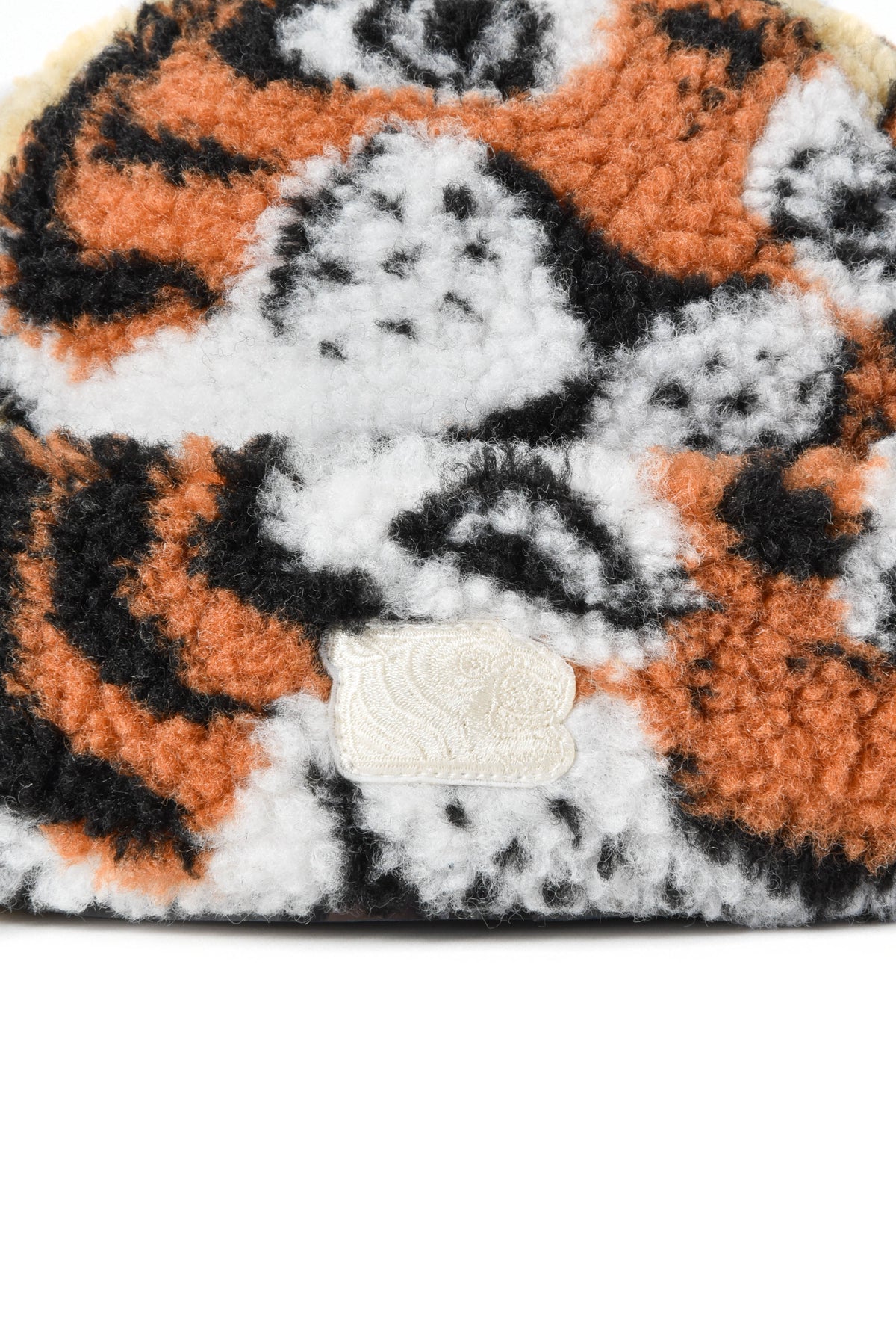 Close-up of a plush tiger patterned item with a brand logo on a white background