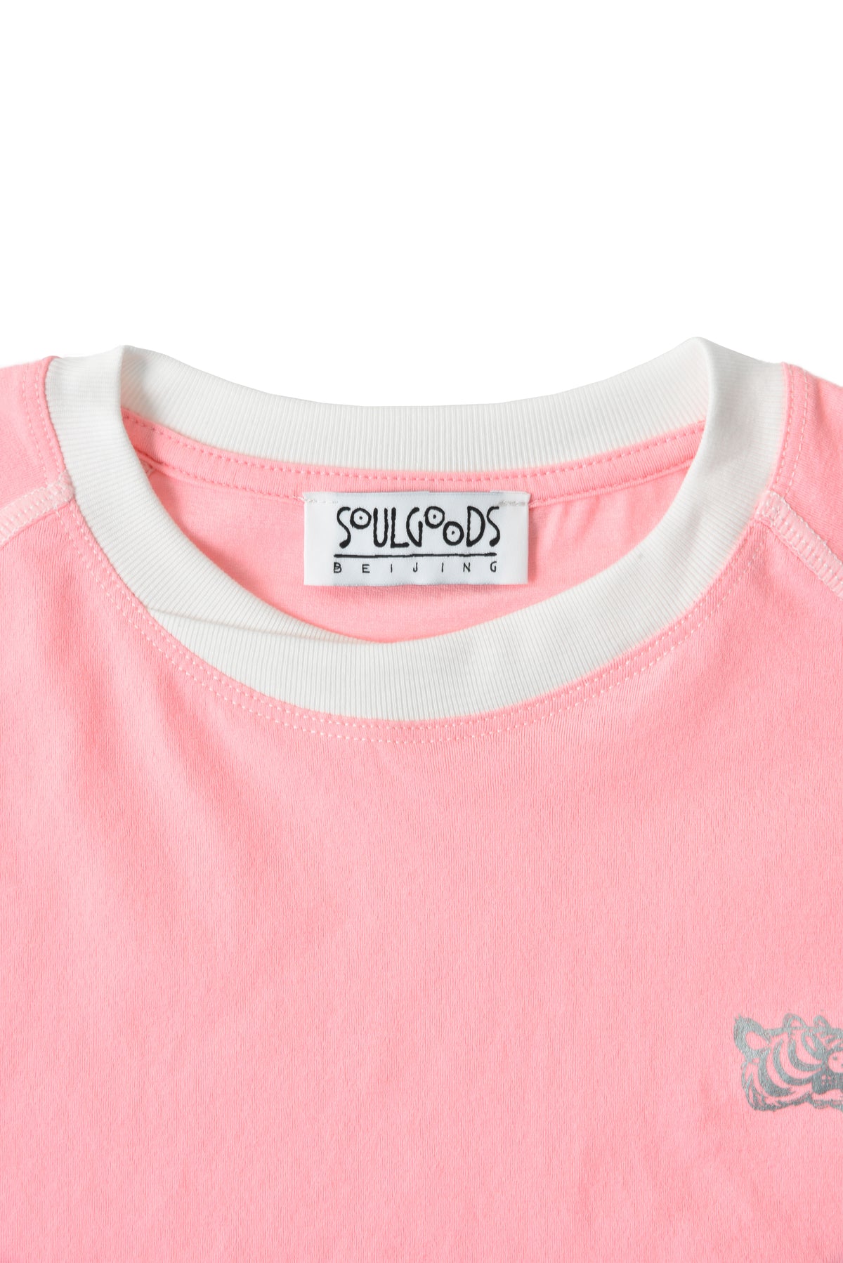 Close-up of a pink shirt with a soulgoods brand label on a white background