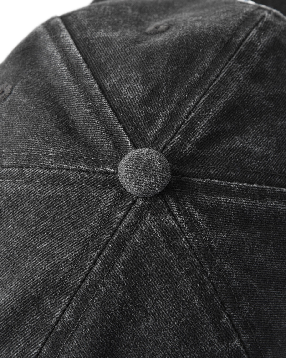 Close-up of a black denim cap with a button detail