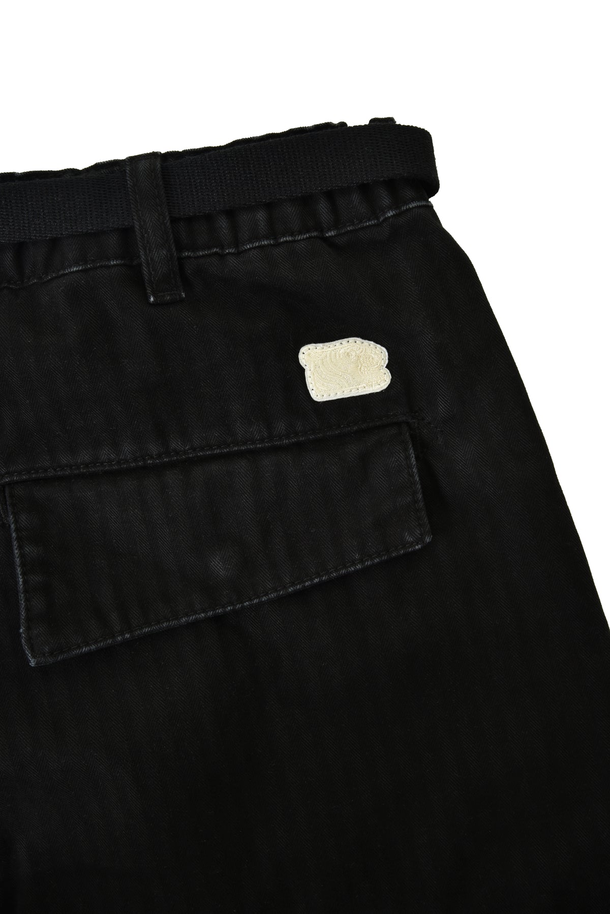Black pants with a beige patch on a white background