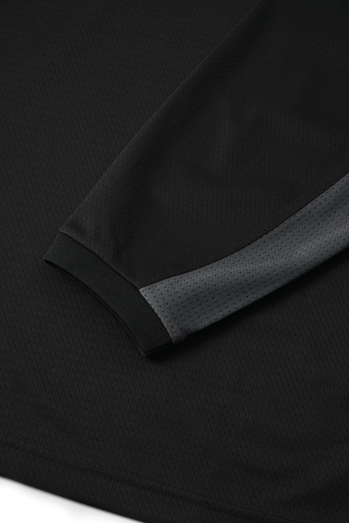 Close-up of a black fabric with a textured trim on a dark background