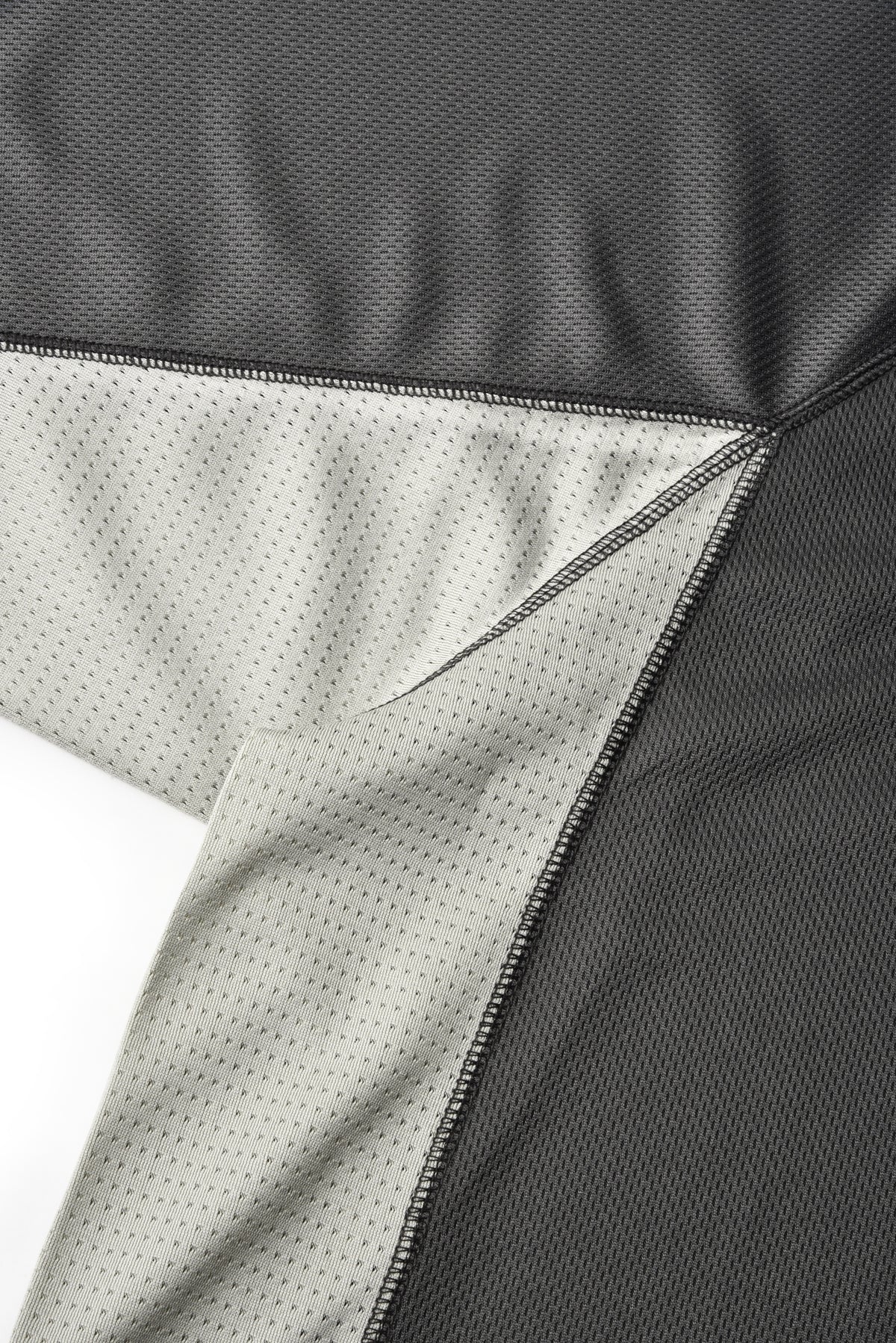 Close-up of a black mesh athletic garment showing the outer fabric and a light gray inner lining with a fine dotted pattern.