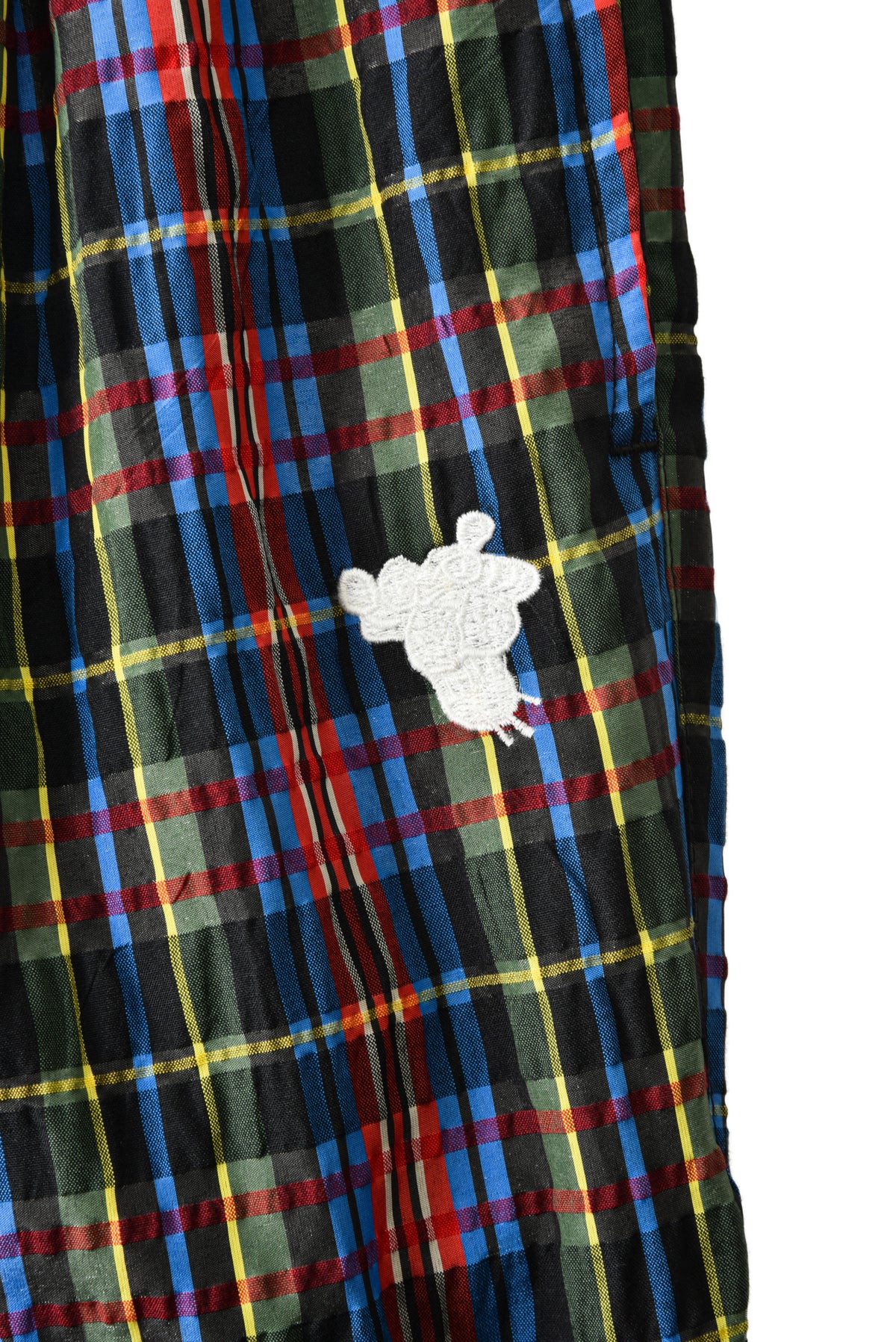 Plaid fabric with a white embroidered soulgoods tiger head design on a white background