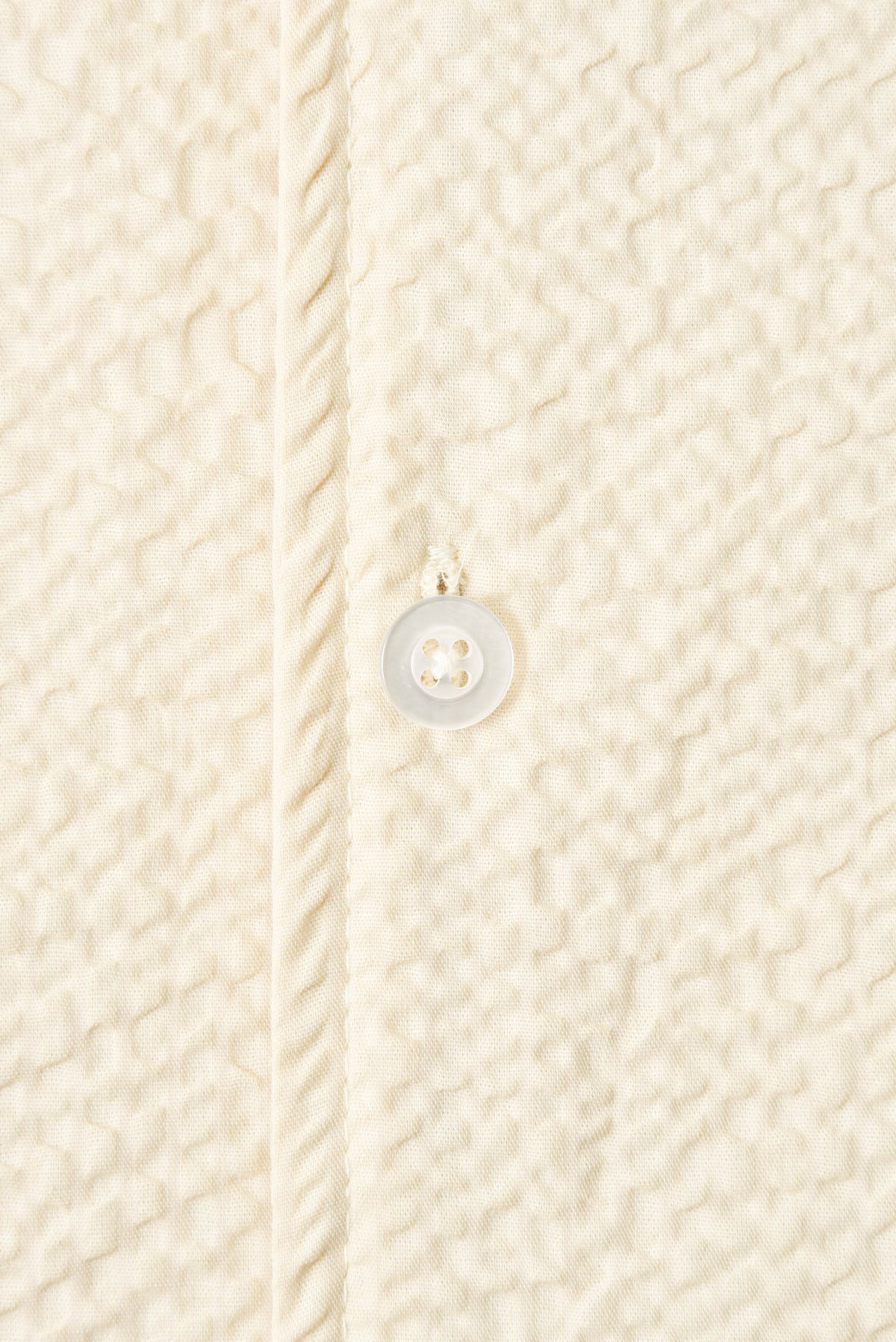 Close-up of a textured beige fabric with a button detail