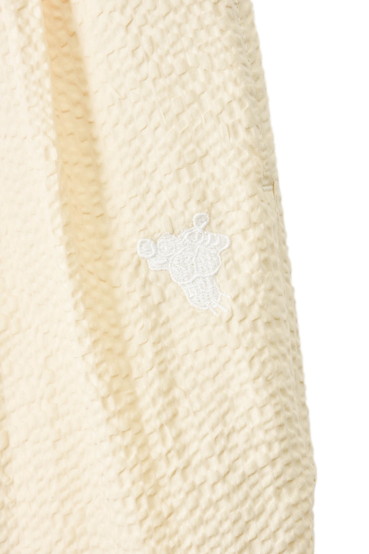 Close-up of a textured beige fabric with a small white soulgoods tiger head logo.