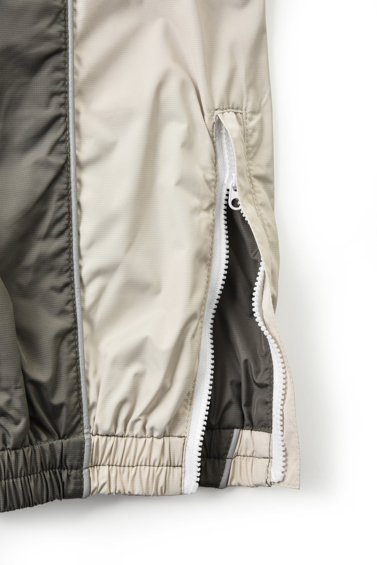 Close-up of a beige and black jacket with a zipper on a white background