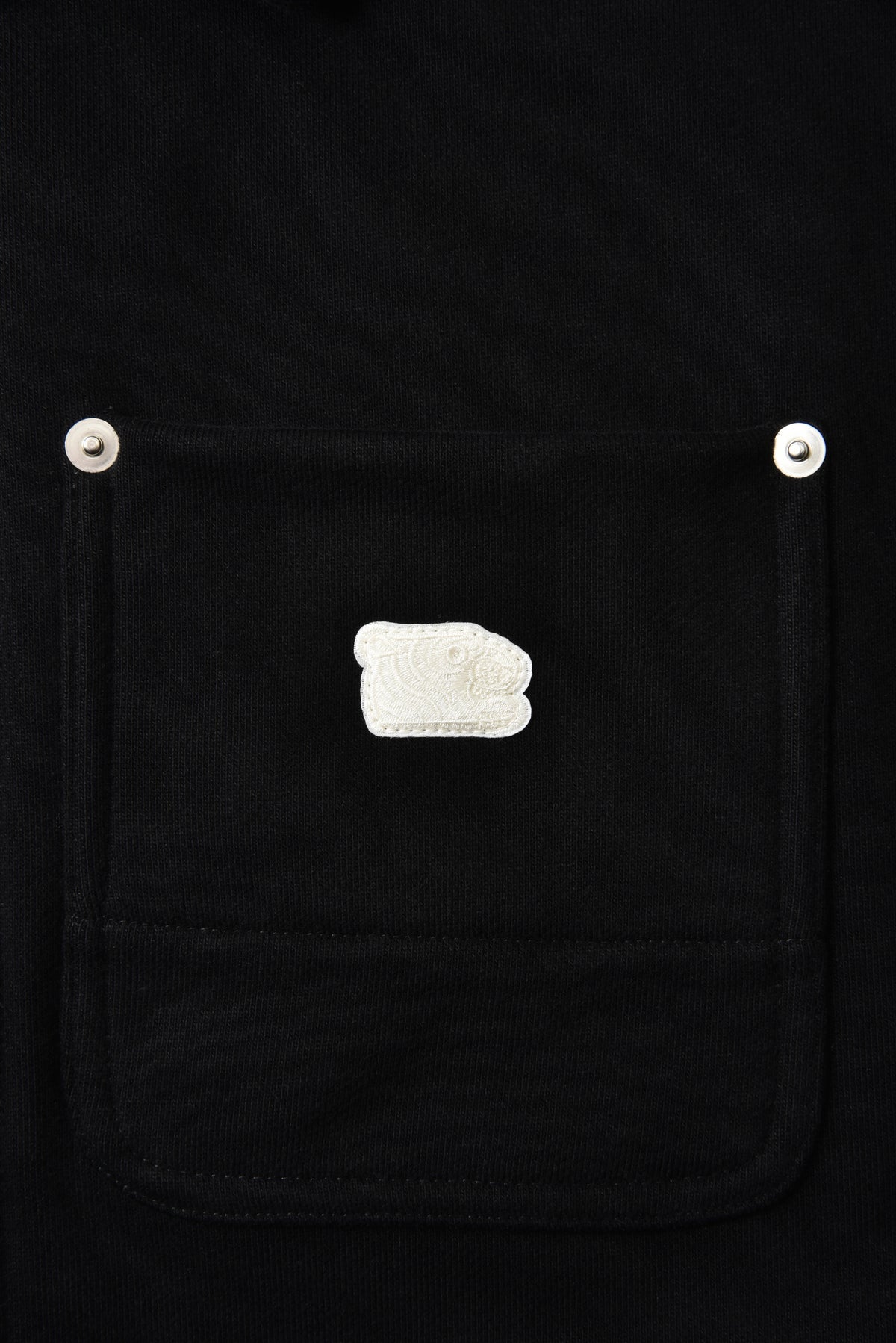Black jacket pocket with a white soulgoods tiger head patch on a black background