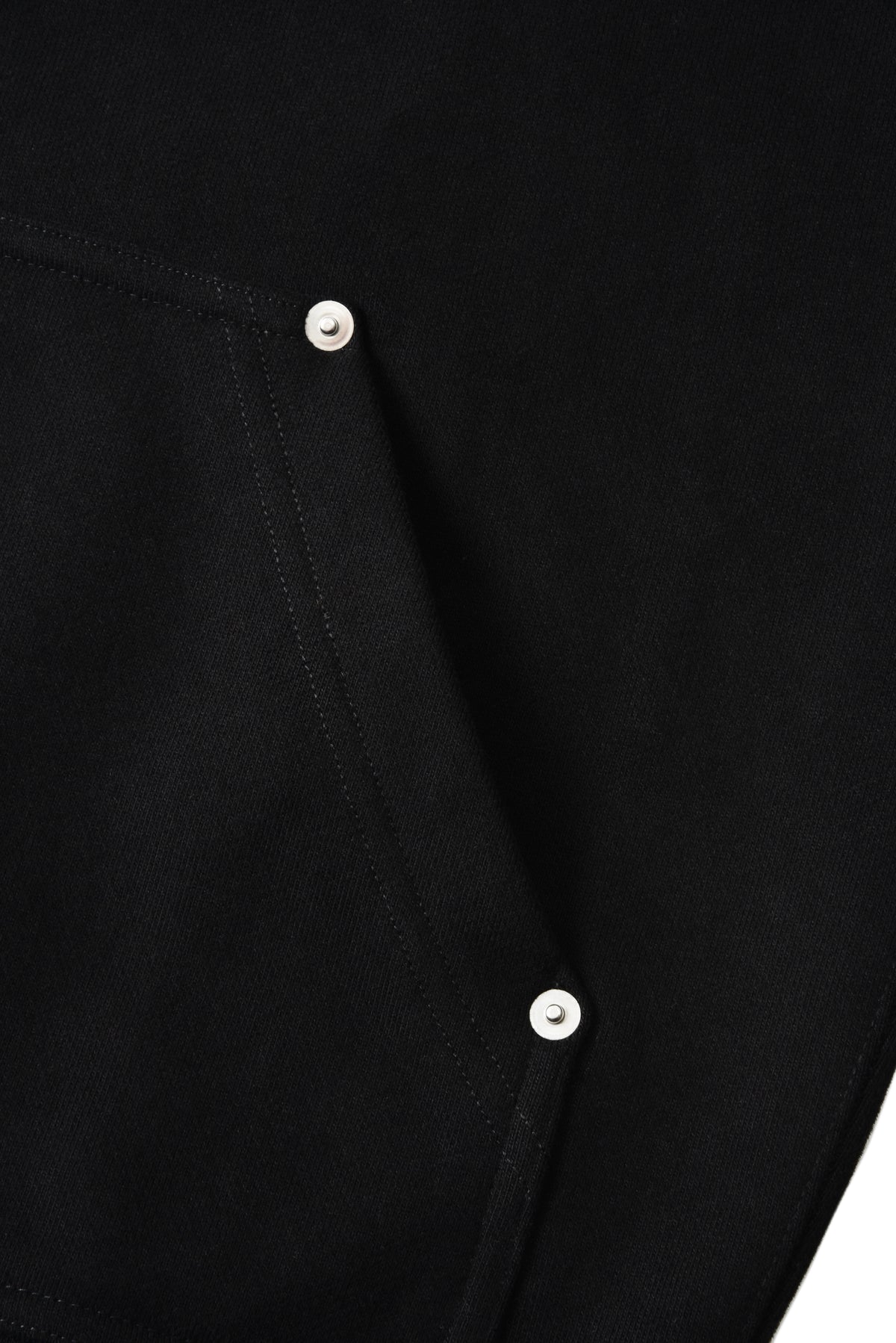 Close-up of a black garment with buttons on a white background