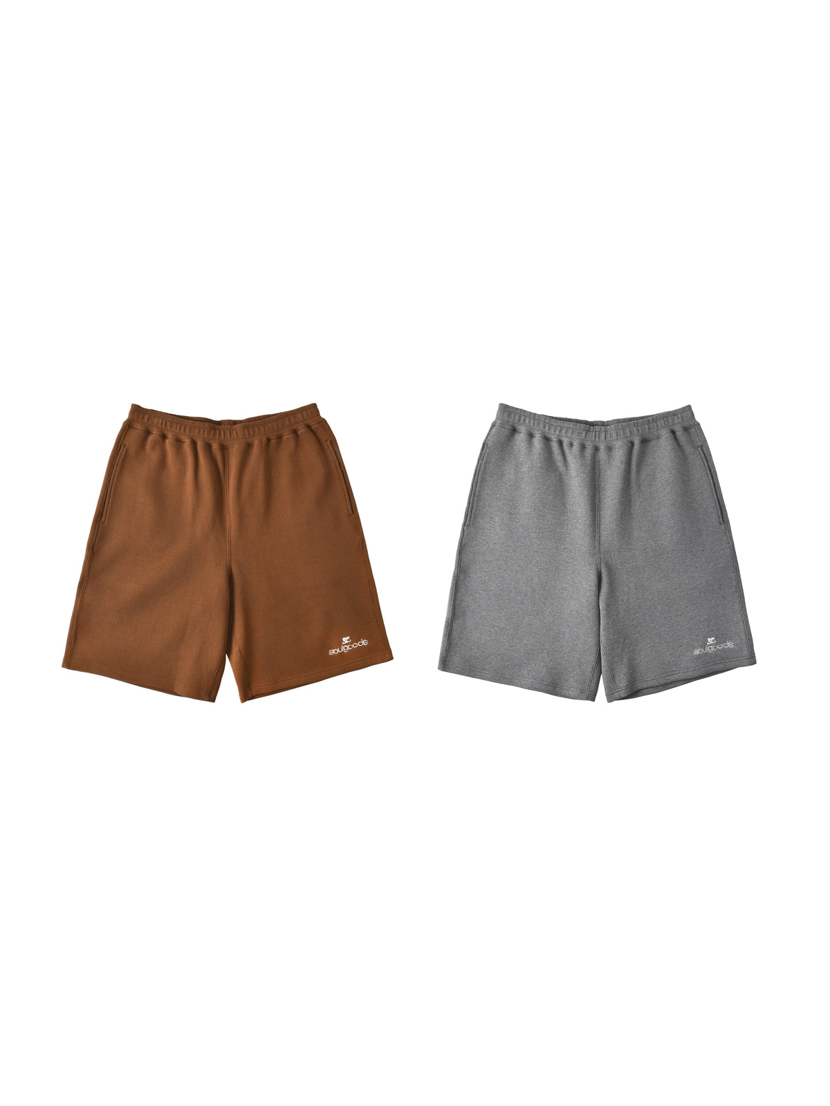 Two pairs of athletic shorts displayed side-by-side on a plain white background. The left pair is a warm brown color with a small white logo on the lower left leg.