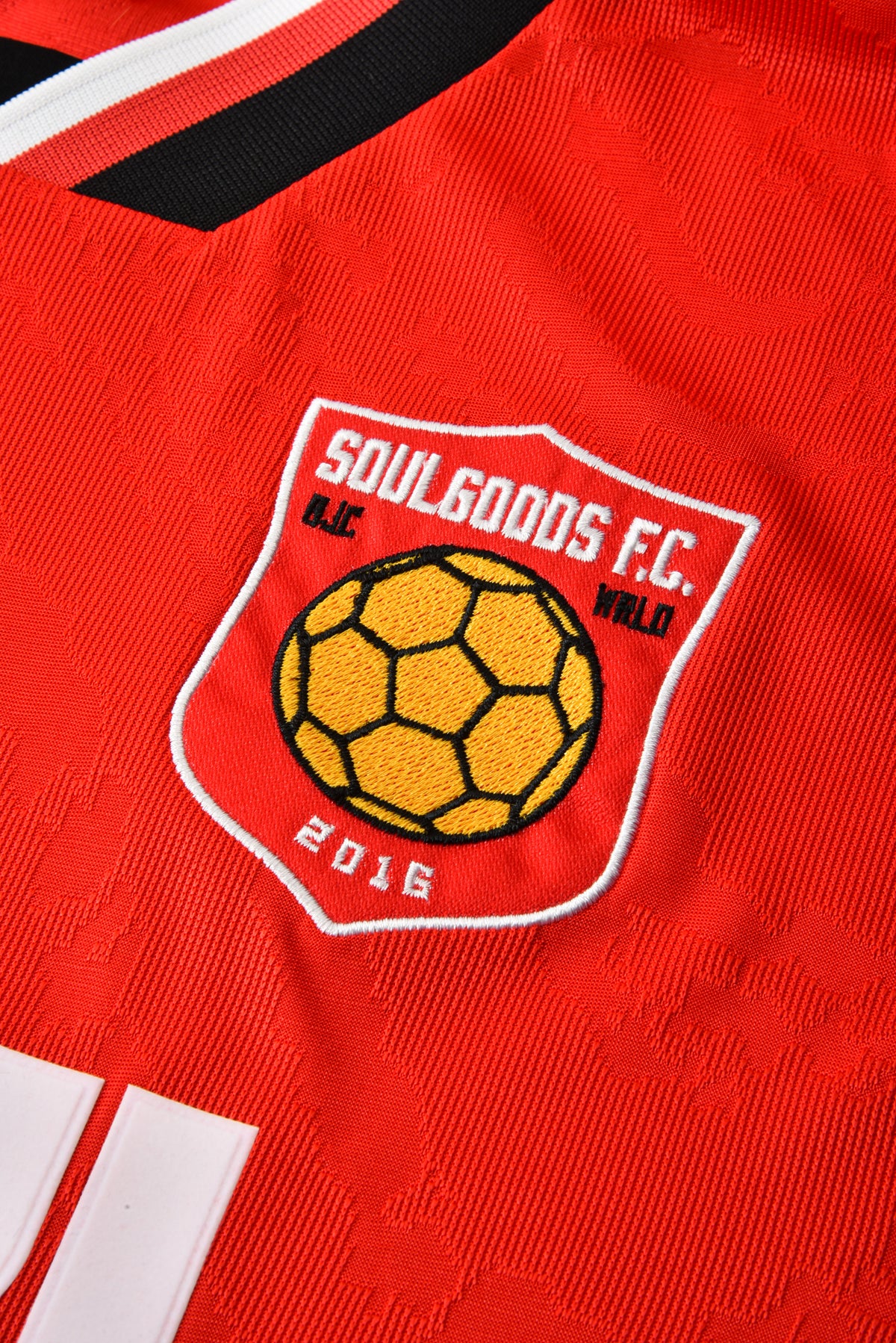 Red sports jersey with a yellow soccer ball logo and text on a white background
