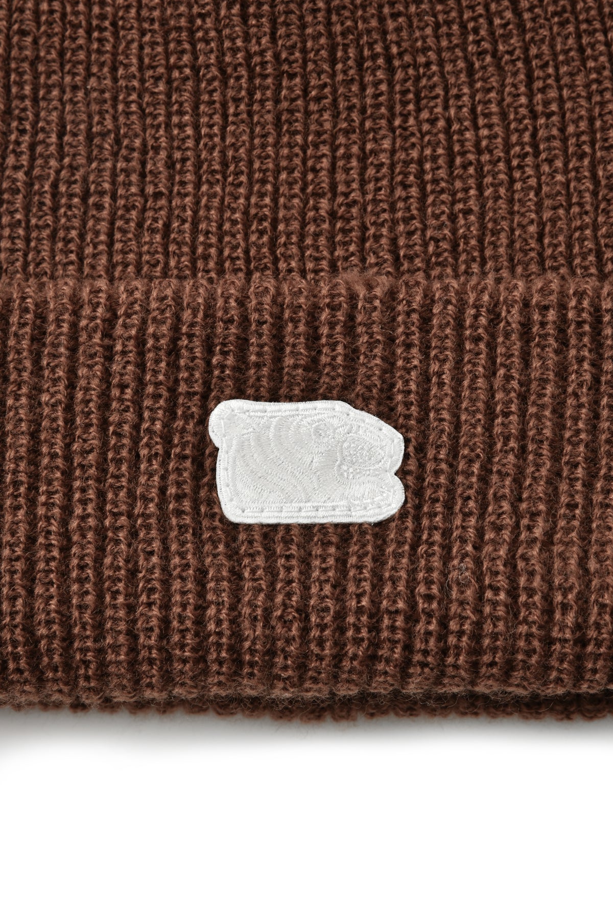 Brown knit beanie with a white soulgoods tiger head logo patch on a white background