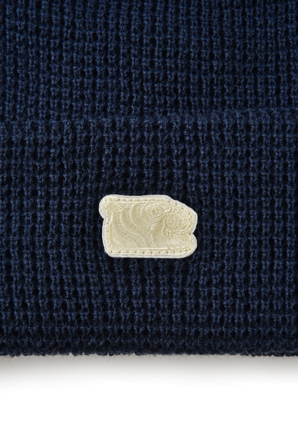 Navy blue fabric with a beige soulgoods tiger head logo patch on a white background