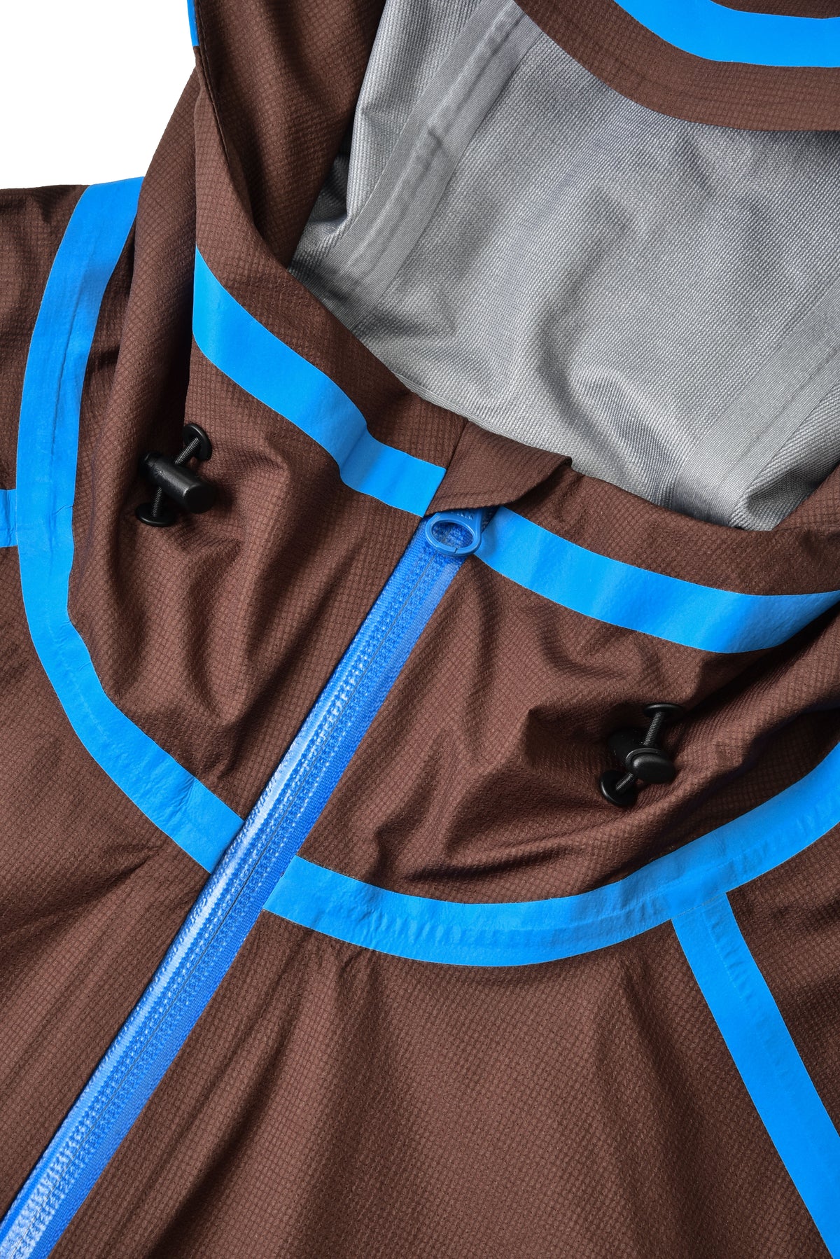 Close-up of a brown garment with blue zippers and buttons.