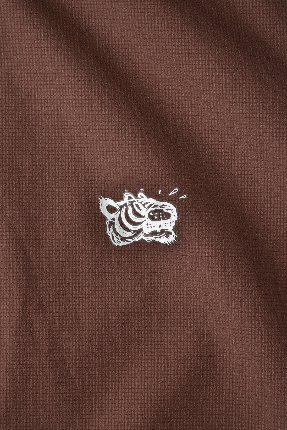 Close-up of a brown textured fabric with a white embroidered tiger design.