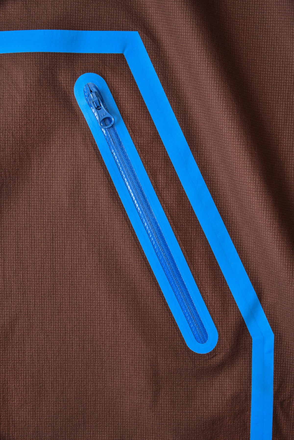 Brown fabric with a blue zipper and geometric design