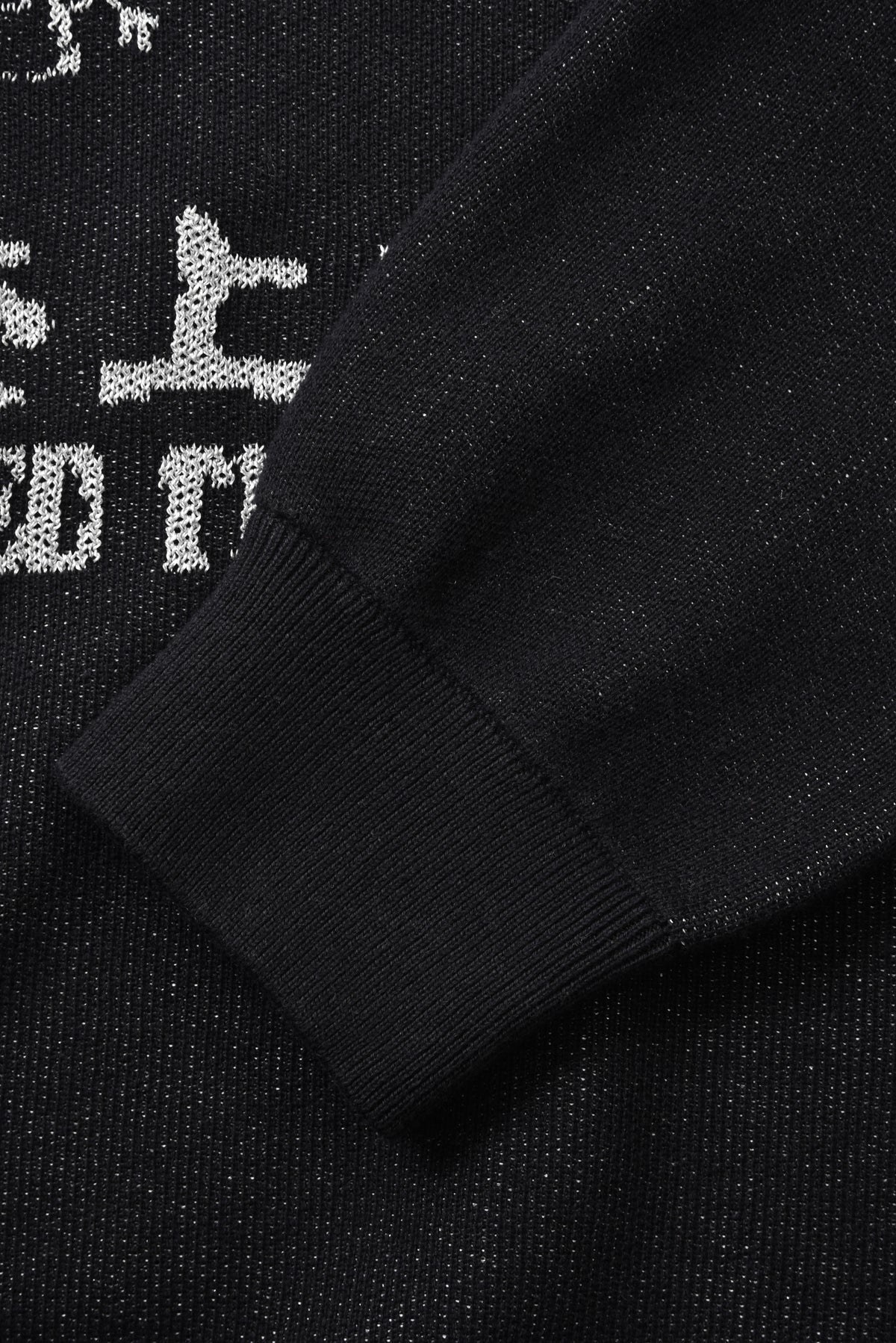 Close-up of a black sweater with white text on a dark background