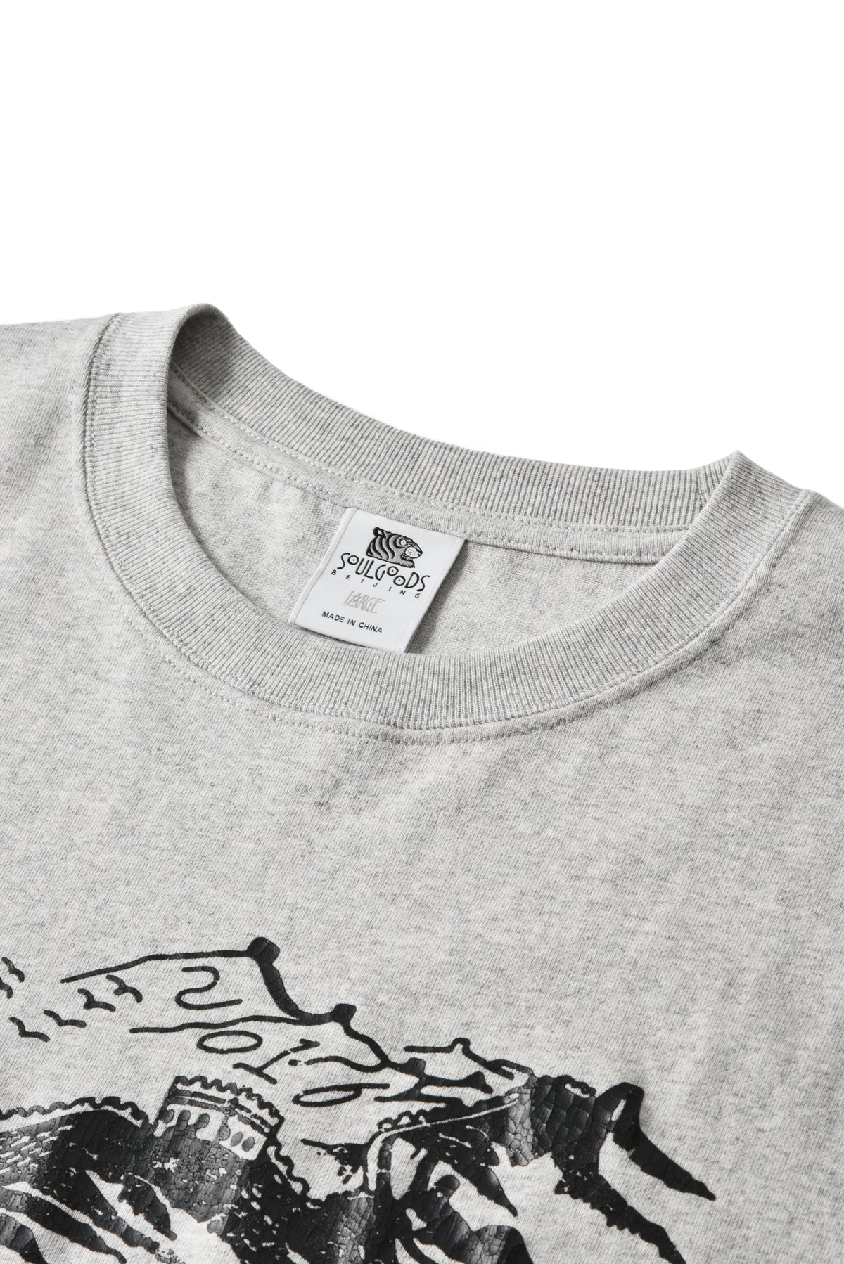Close-up of a light heather gray crewneck sweatshirt showing the inner neck label and a black graphic print on the front.
