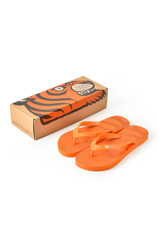 Orange flip-flop sandals with a tiger-stripe pattern, shown next to their cardboard packaging box which features a matching tiger illustration.