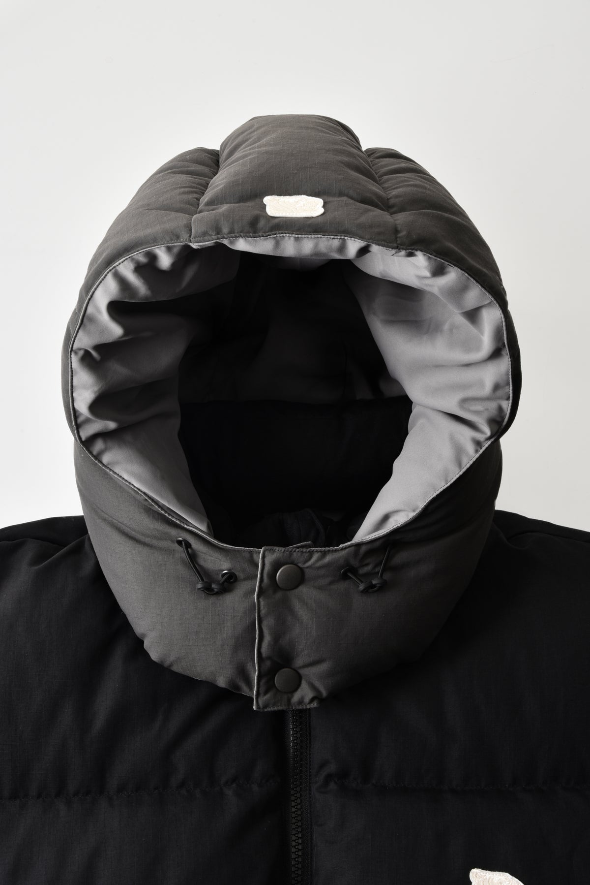 Close-up of a black winter coat with a hood on a white background