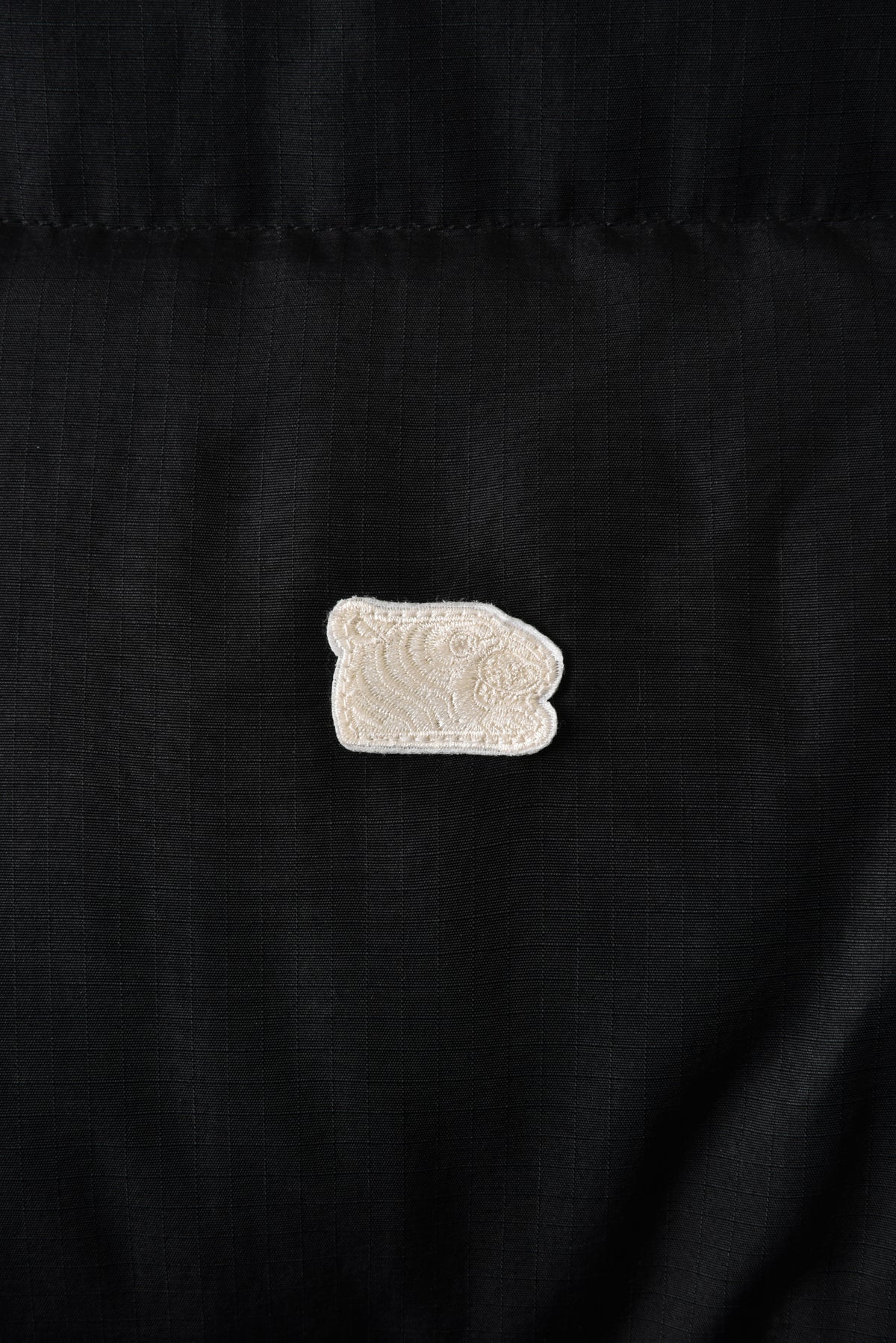 Black fabric with a white tiger head embroidered patch featuring a floral design.